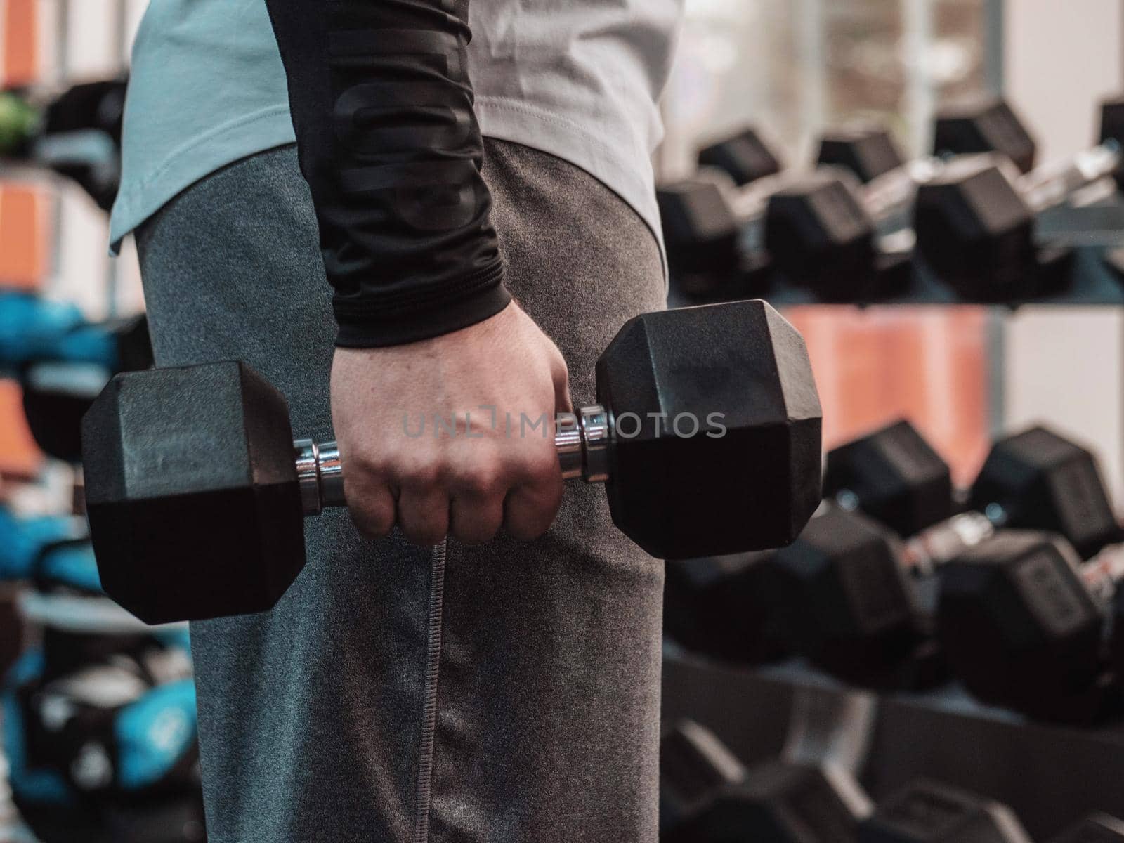 Powerful bodybuilder doing the exercises with dumbbells. Photo of strong male in the gym. Strength and motivation.