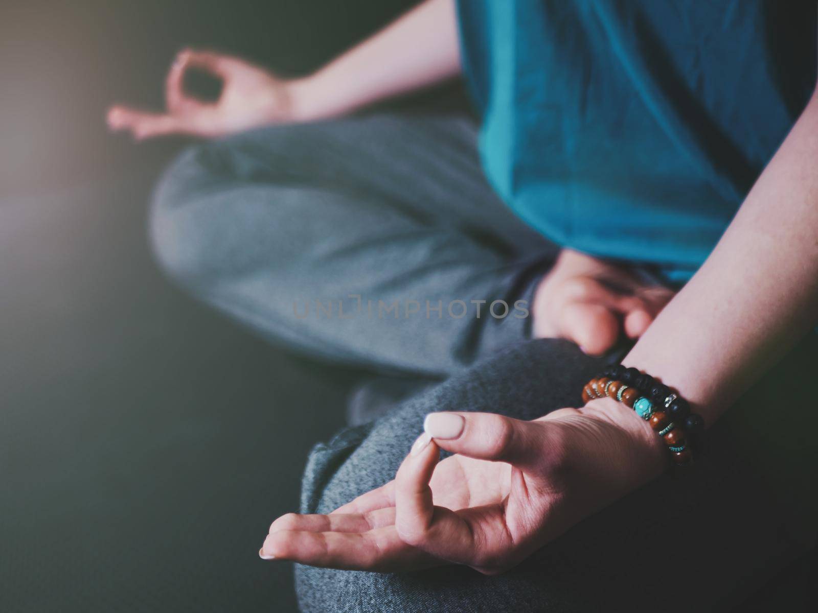 Closeup of woman's hands with bracelets meditating in lotus pose indoors. Gyan mudra. Yoga, religion concept.
