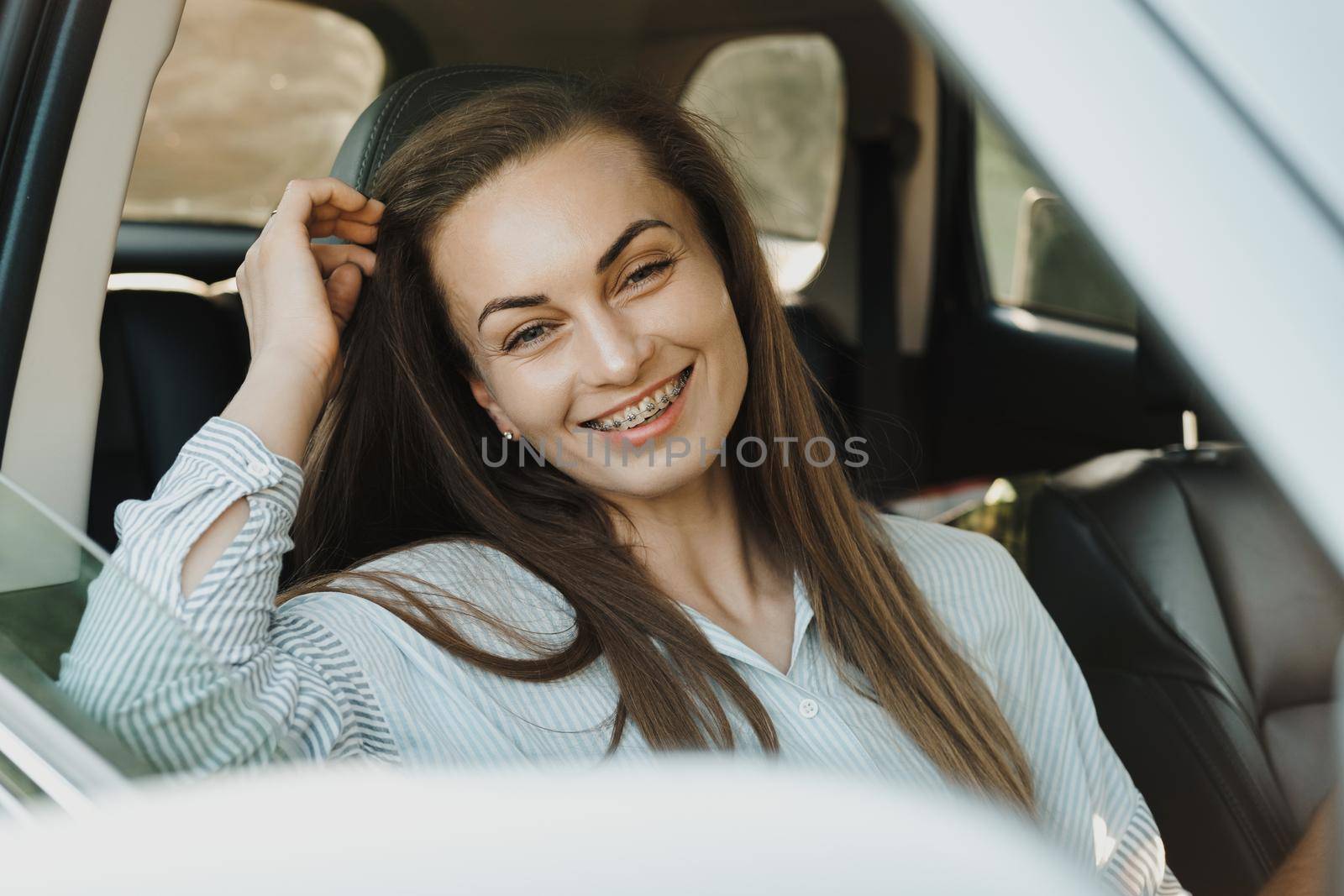Middle aged woman with dental braces smile while sitting inside car by Romvy