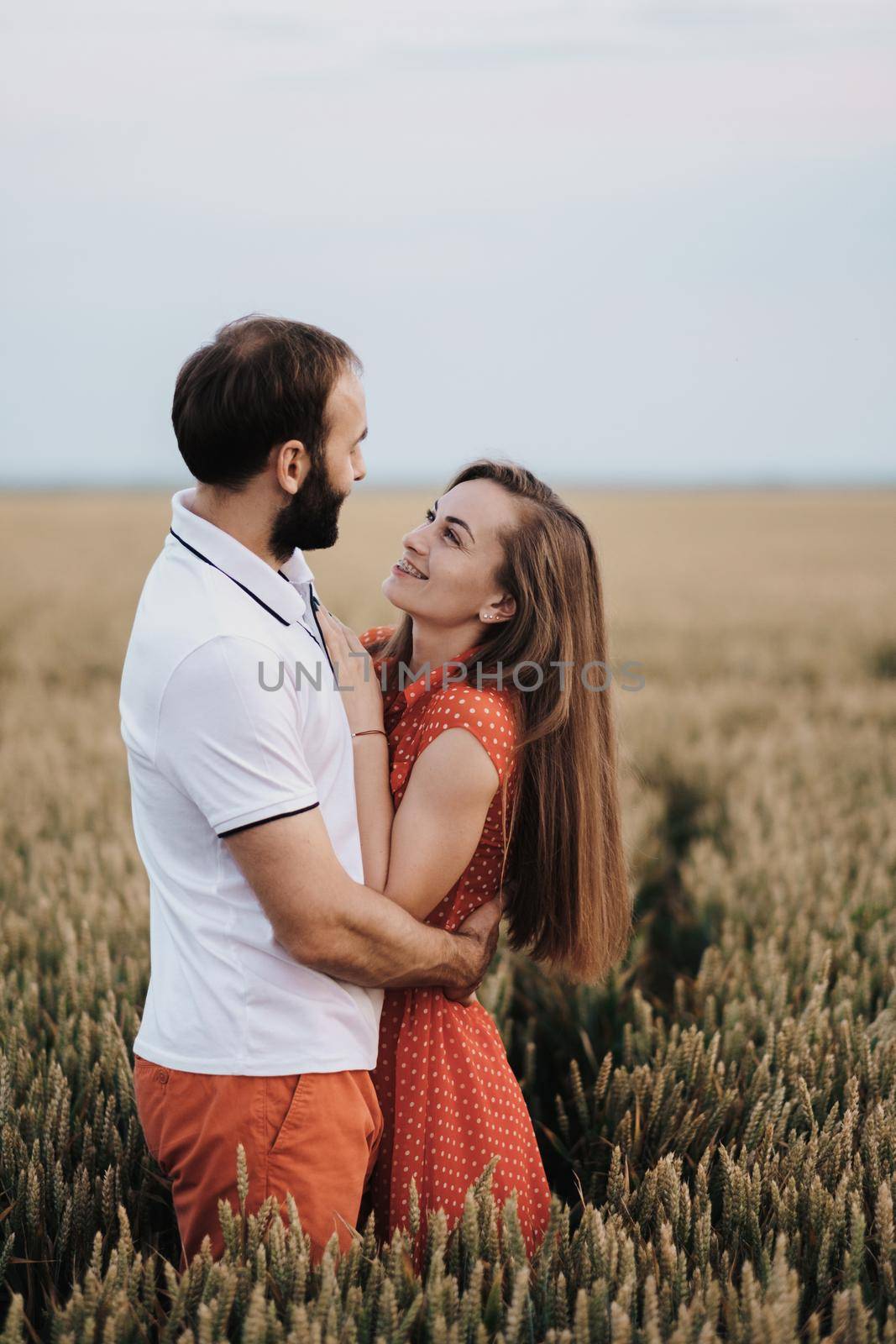 Happy middle-aged couple hugging in the wheat field, caucasian cheerful woman and man in love standing together outdoors by Romvy