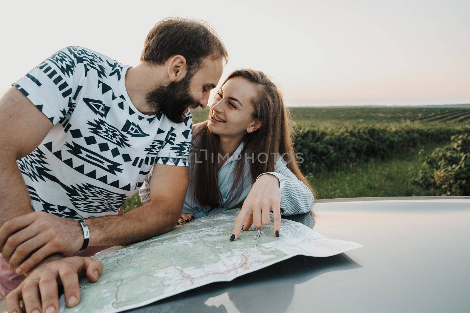 Middle Aged Couple on a Road Trip, Caucasian Man and Woman Planning Next Stop on Map on Car Hood by Romvy