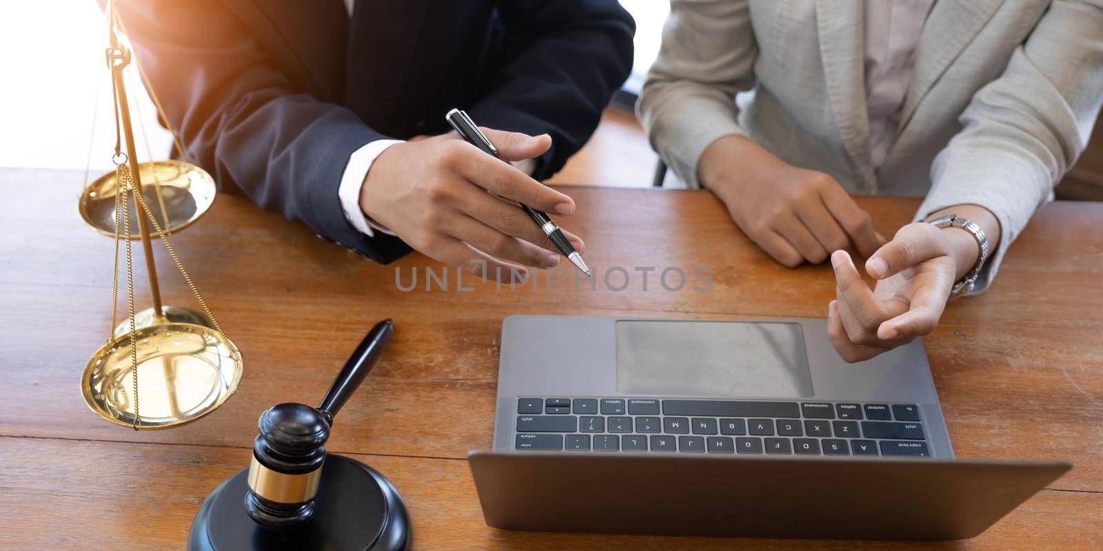 Notary lawyers or judges consult or discuss contract documents with business clients in the office. Legal and legal services concept with hammer and scales with a laptop on the table..