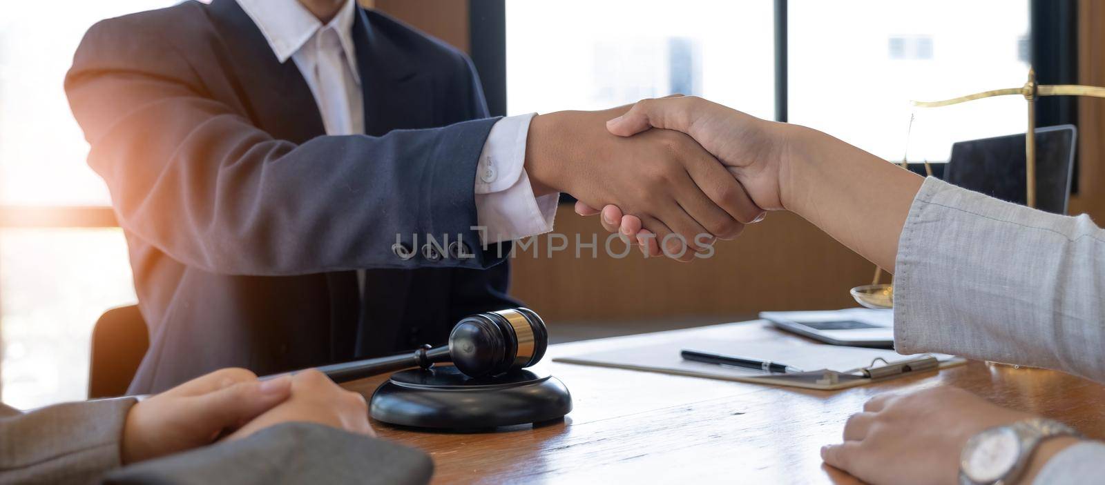 Businessman shaking hands to seal a deal with his partner lawyers or attorneys discussing a contract agreement. by wichayada