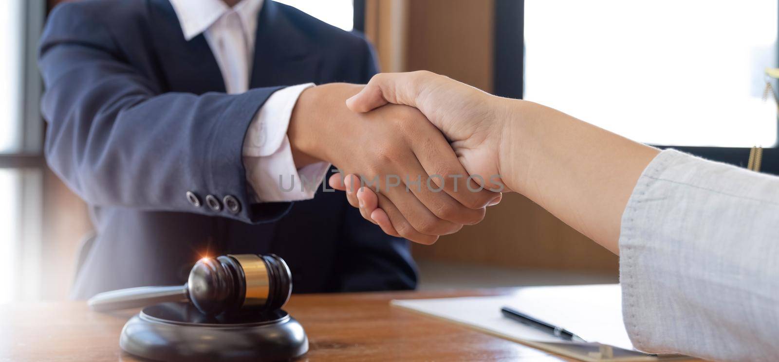 Businessman shaking hands to seal a deal with his partner lawyers or attorneys discussing a contract agreement by wichayada