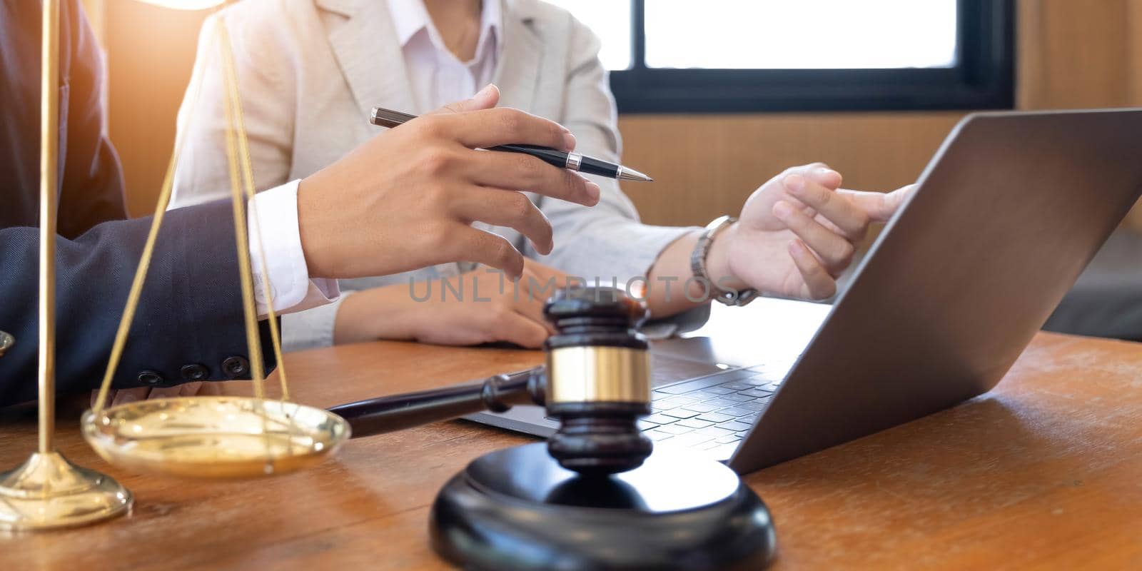 Business and lawyers discussing contract papers with brass scale on desk in office. Law, legal services, advice, justice and law concept picture with film grain effect.