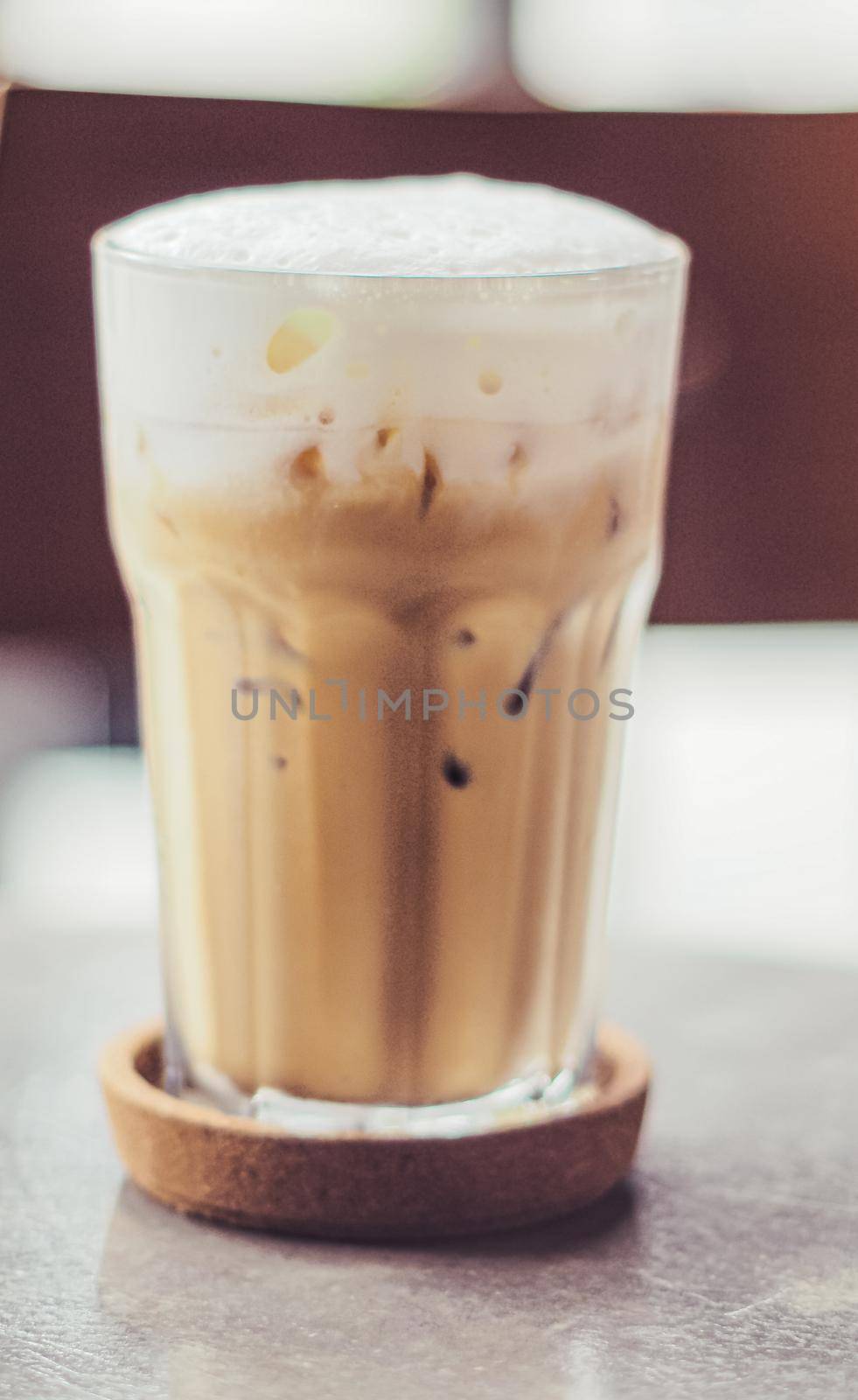 Iced coffee in a clear tall glass with milk or cream on top