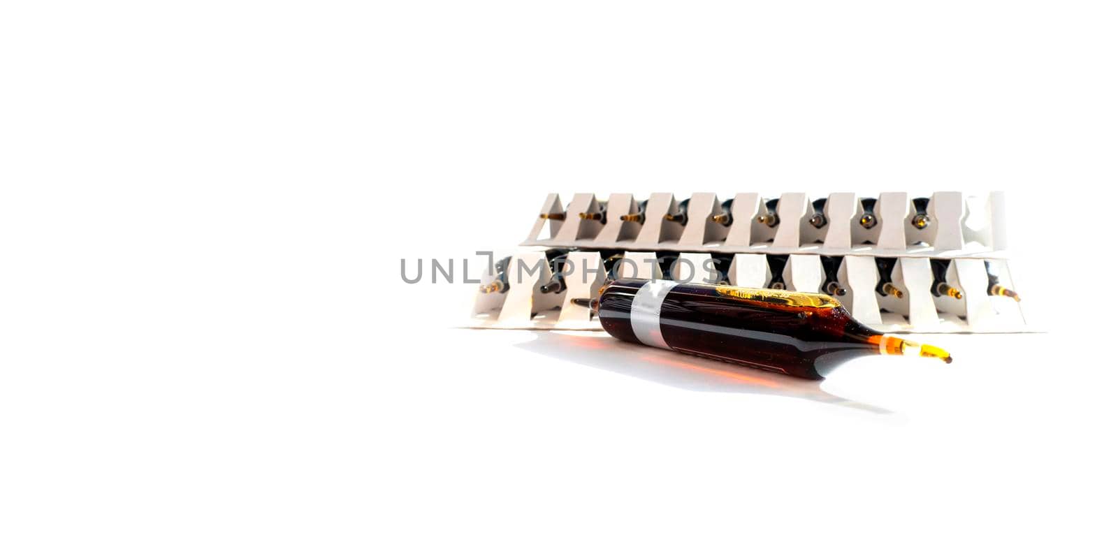 Group object of liquid medicinal agent in limpid glassware in medical laboratory. Group of ampoules with a transparent medicine in medical laboratory. horizontal perspective view of many brown ampoules set in pharmaceutical packaging white container