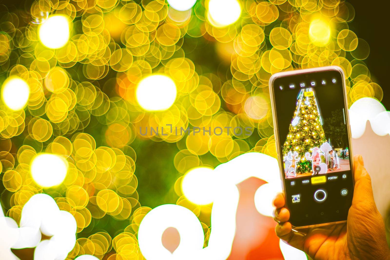 hand holding mobile smart phone with Christmas light decorated background