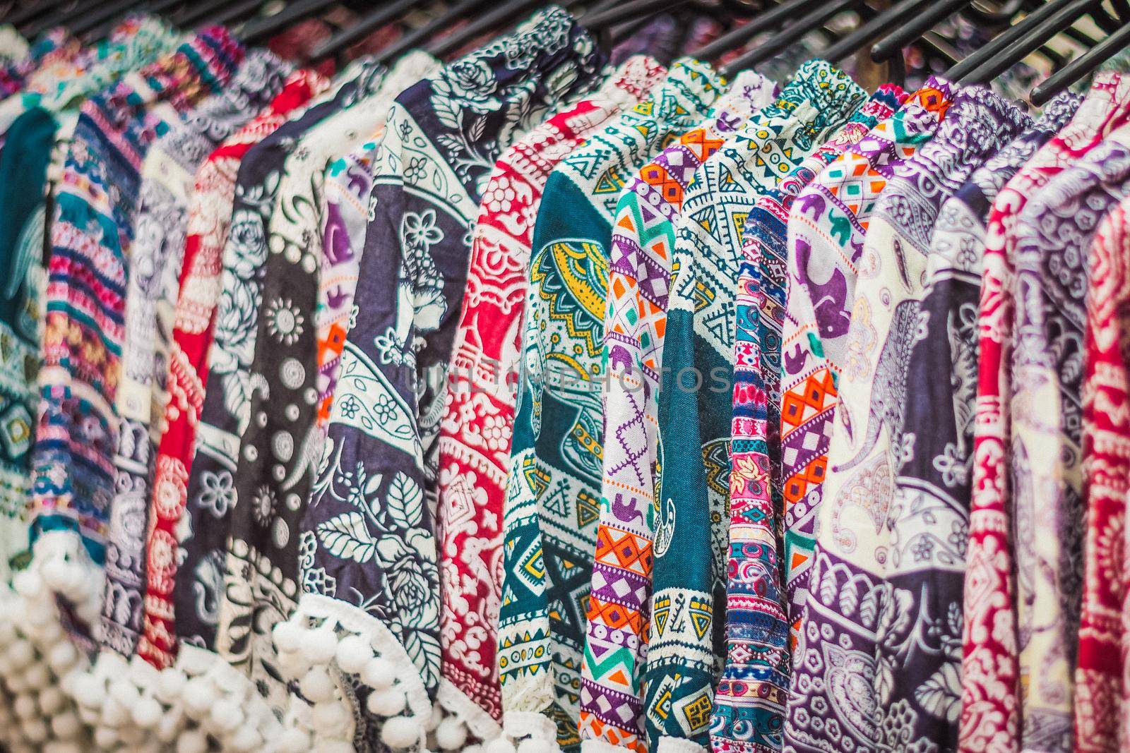 clothes hanging on a rack in a flea market Souvenir shop in Thailand by Petrichor