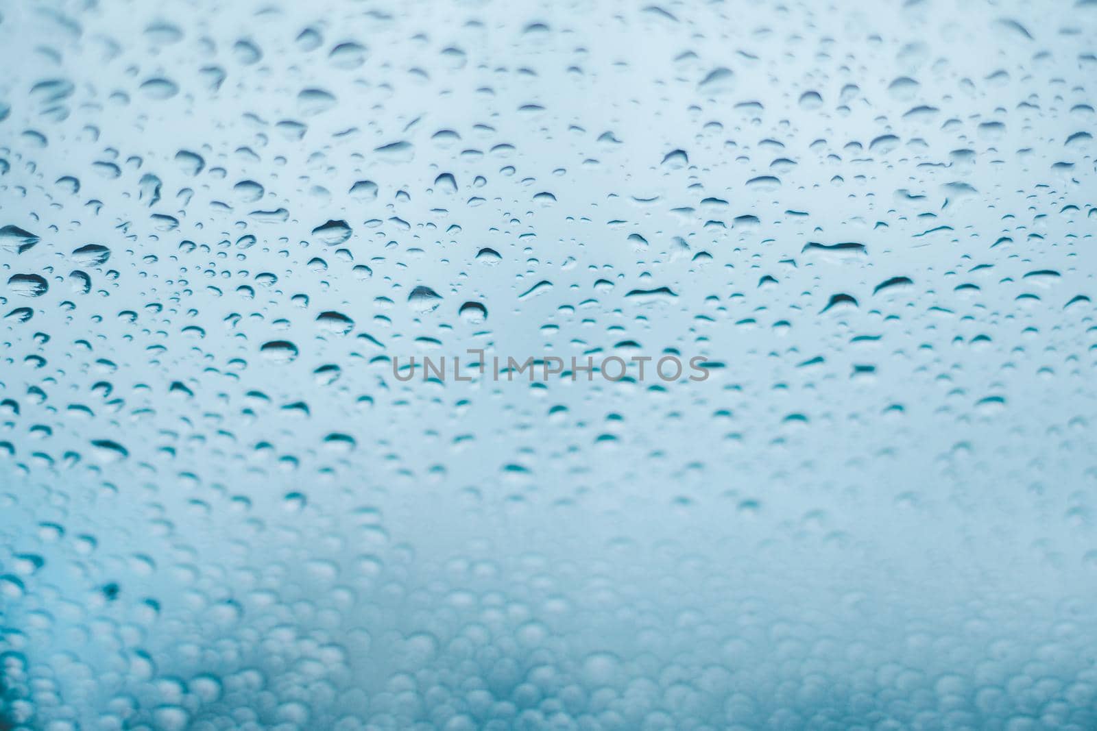 Raindrops on the window. Water droplets on glass. Blue tone