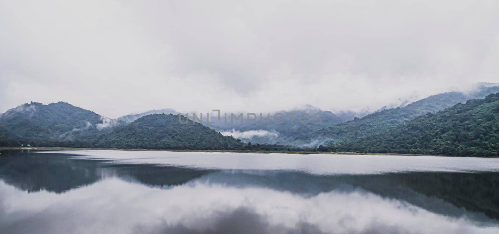 Panorama view of  mountains Lake with tropical trees forest . Beautiful A Calm Lake With Mountain ranges on background . Wonderful atmospheric landscape