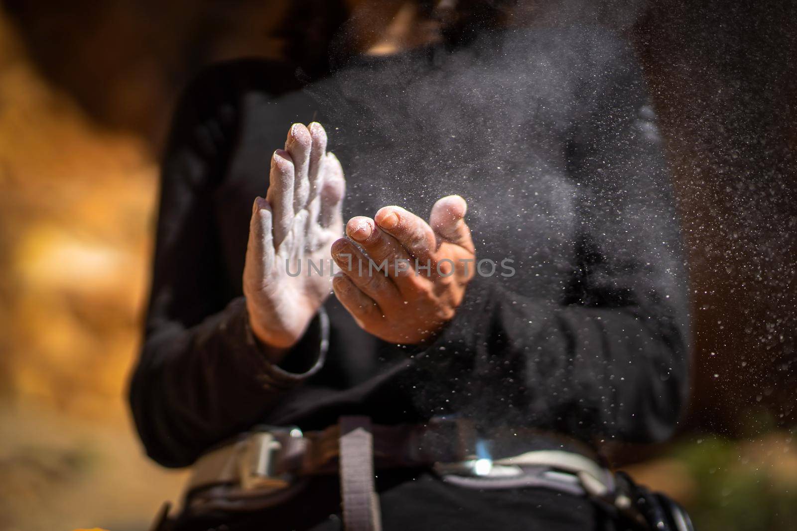 The girl is engaged in rock climbing, uses white powder of magnesia, claps her hands close-up, the woman leads an active lifestyle, climbs the mountains outdoor.