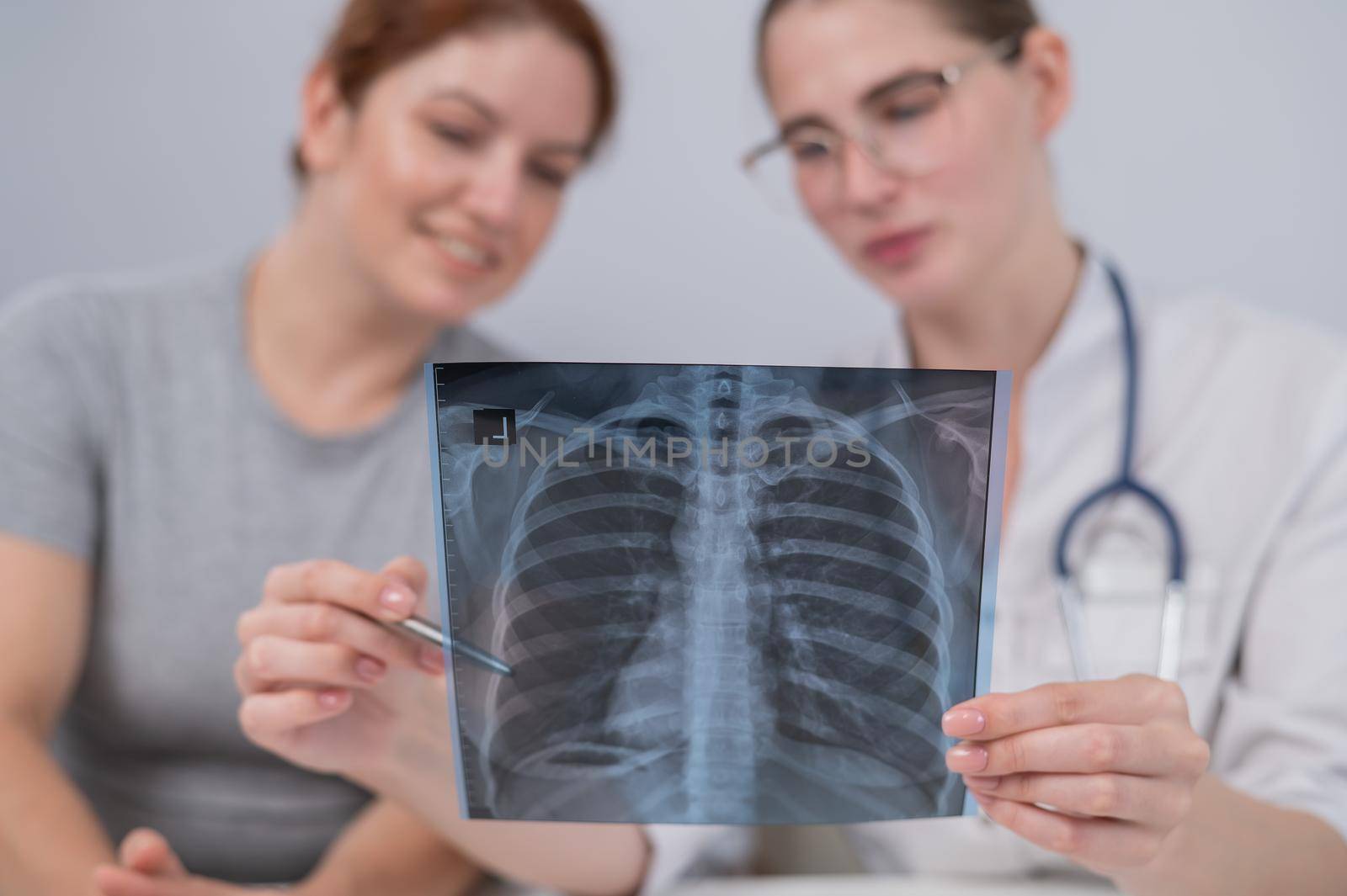 The doctor consults a caucasian woman and comments on the x-ray of the lungs