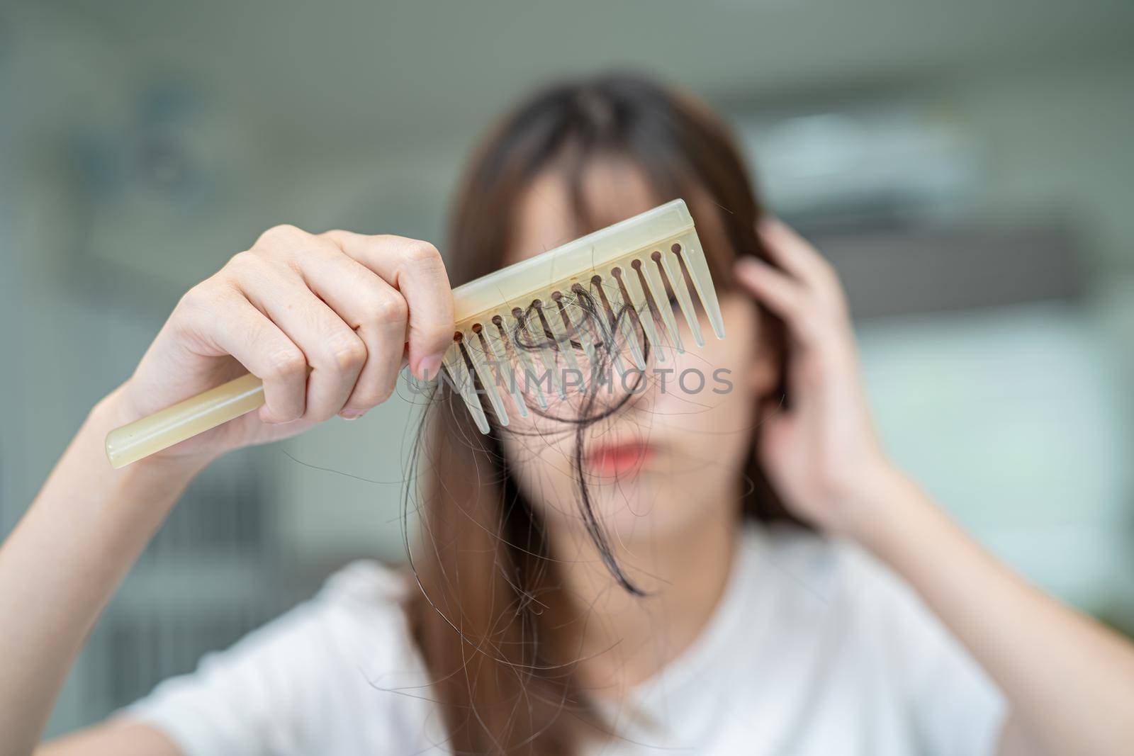 Asian woman have problem with long hair loss attach to comb brush. by pamai