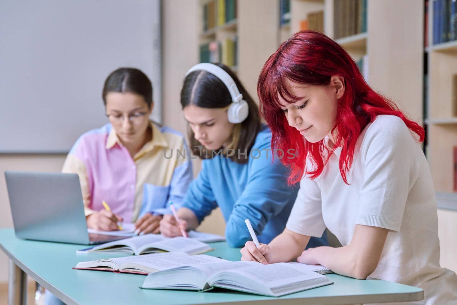 Group of teenage students study at their desks in library class by VH-studio