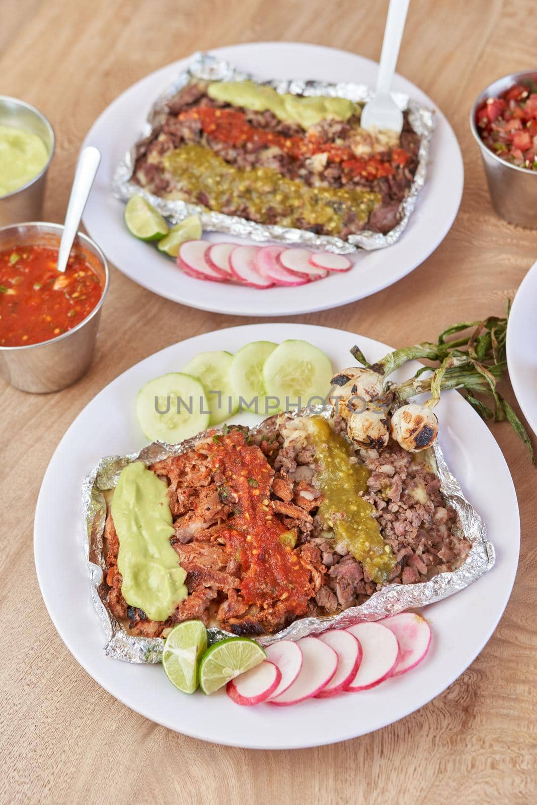 variety of delicious typical mexican food and ingredients such as salsas, red, green, guacamole, lemon, tomato and onion.