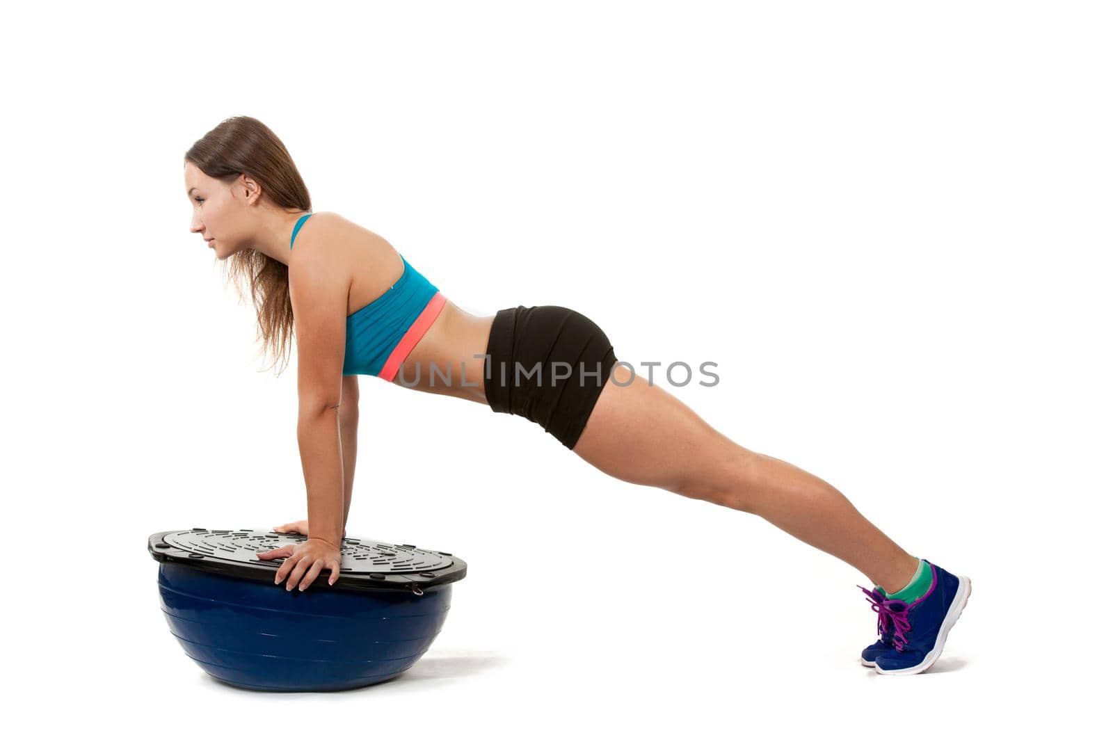 Young sports girl does exercises push-ups on spotrivnom simulator bosu. Portrait in full growth. View profile.