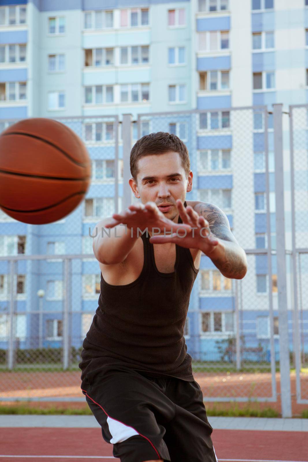 The player on the basketball court amid residential area throws the ball into the side of the camera. by studiodav