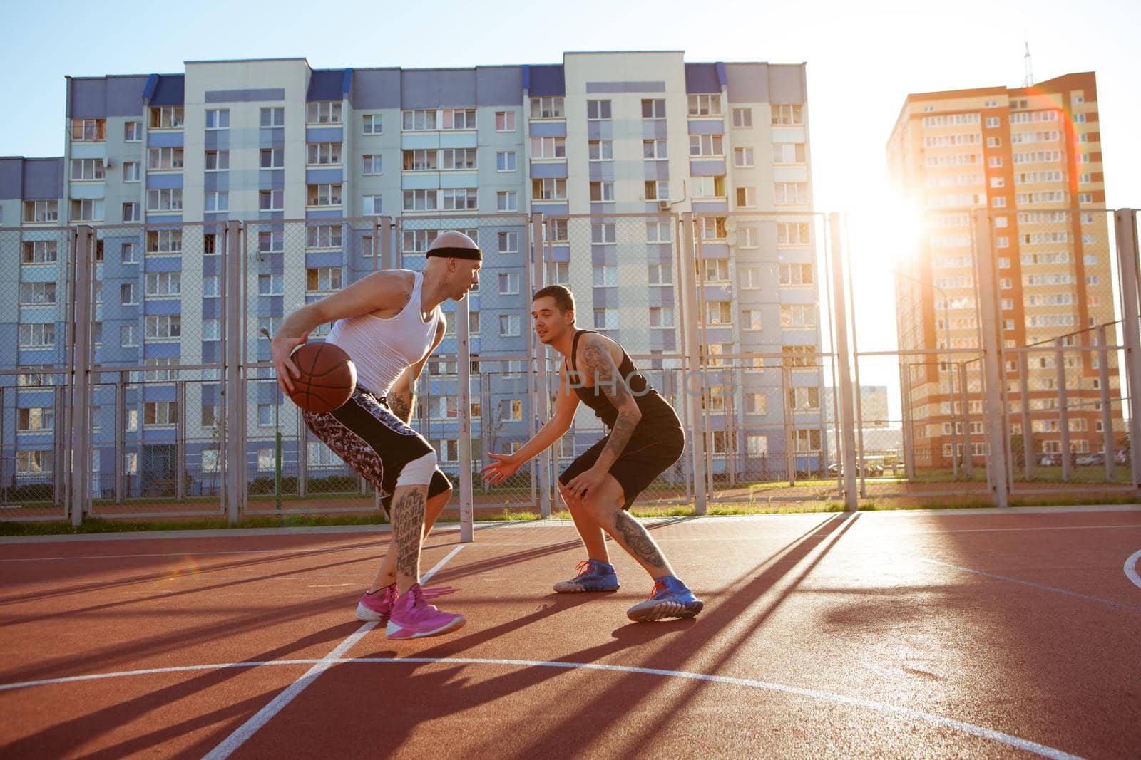 Two guys jump stretch to the ball on the basketball court. Backlight. Sun in the sunset.