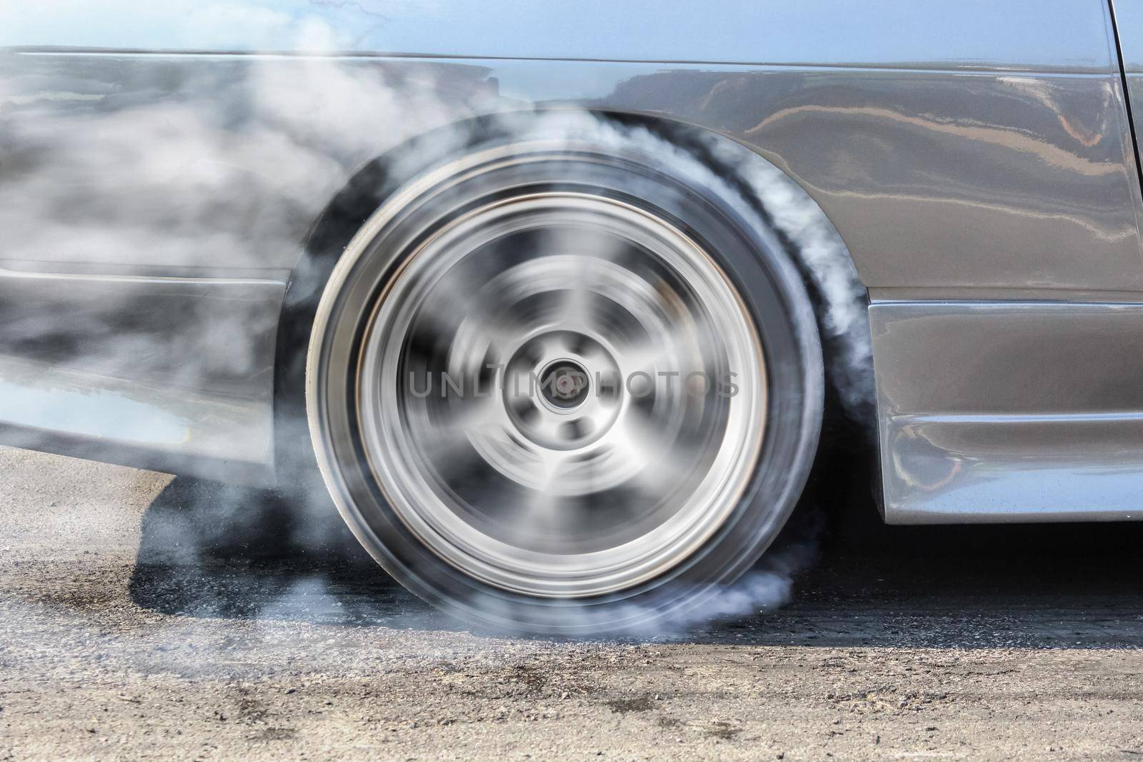 race car burns rubber off its tires in preparation for the race