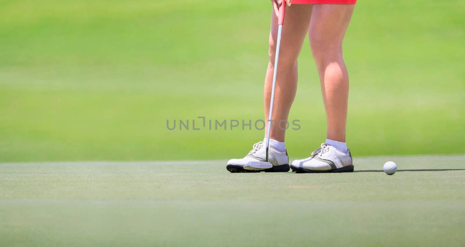 Female golfer putting on green. by toa55