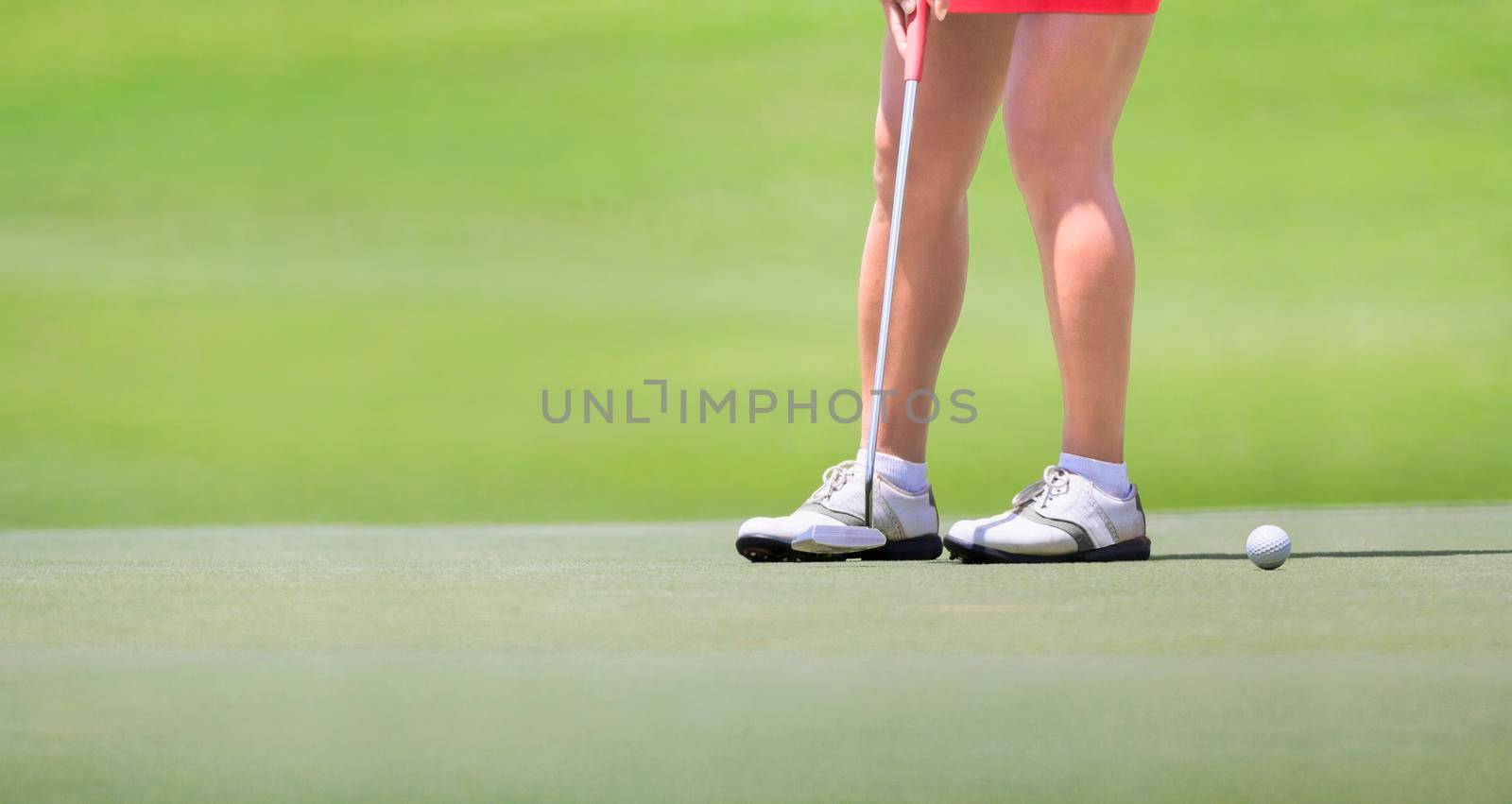 Female golfer putting on green.