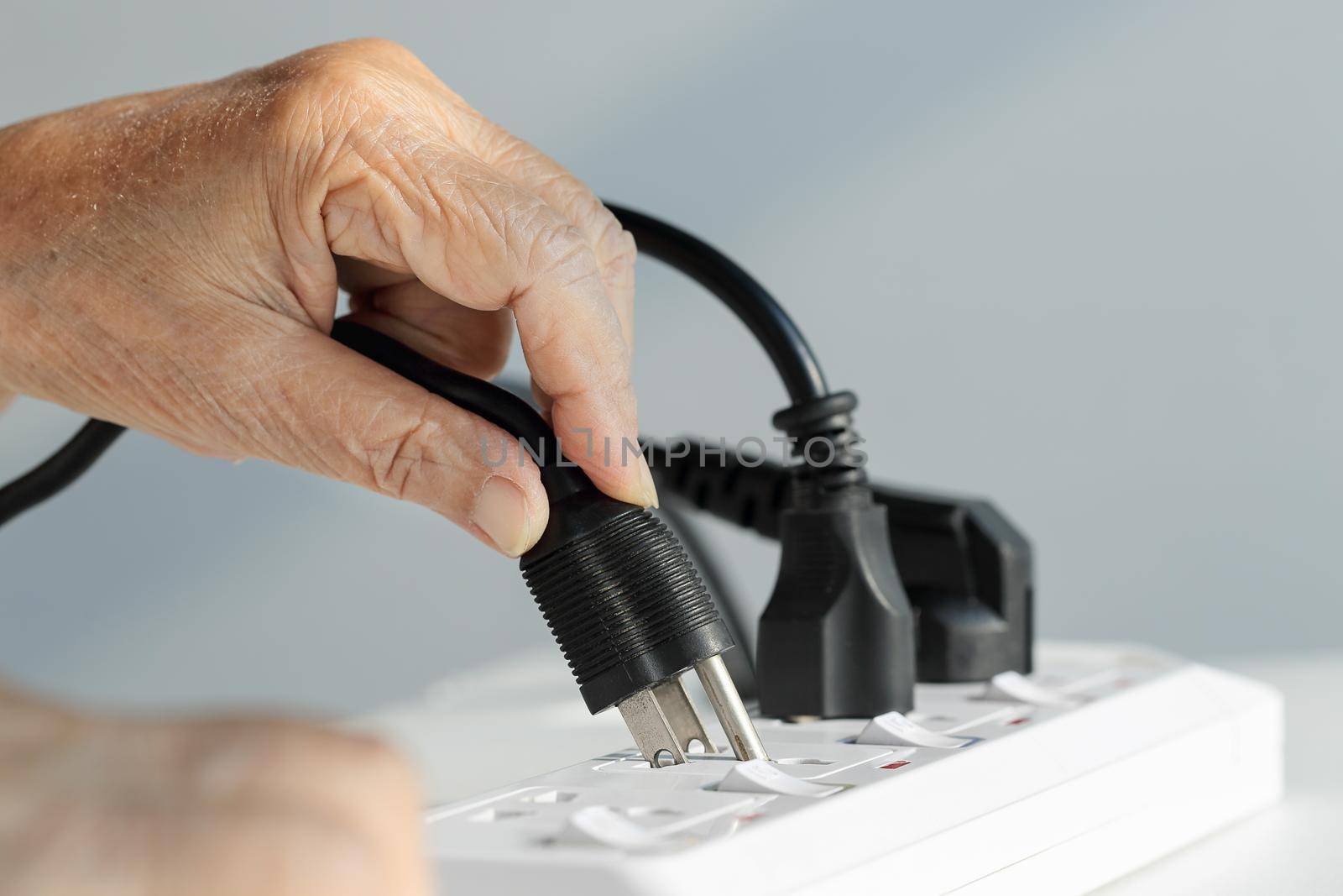 Close up Elderly hand plugging into electrical outlet