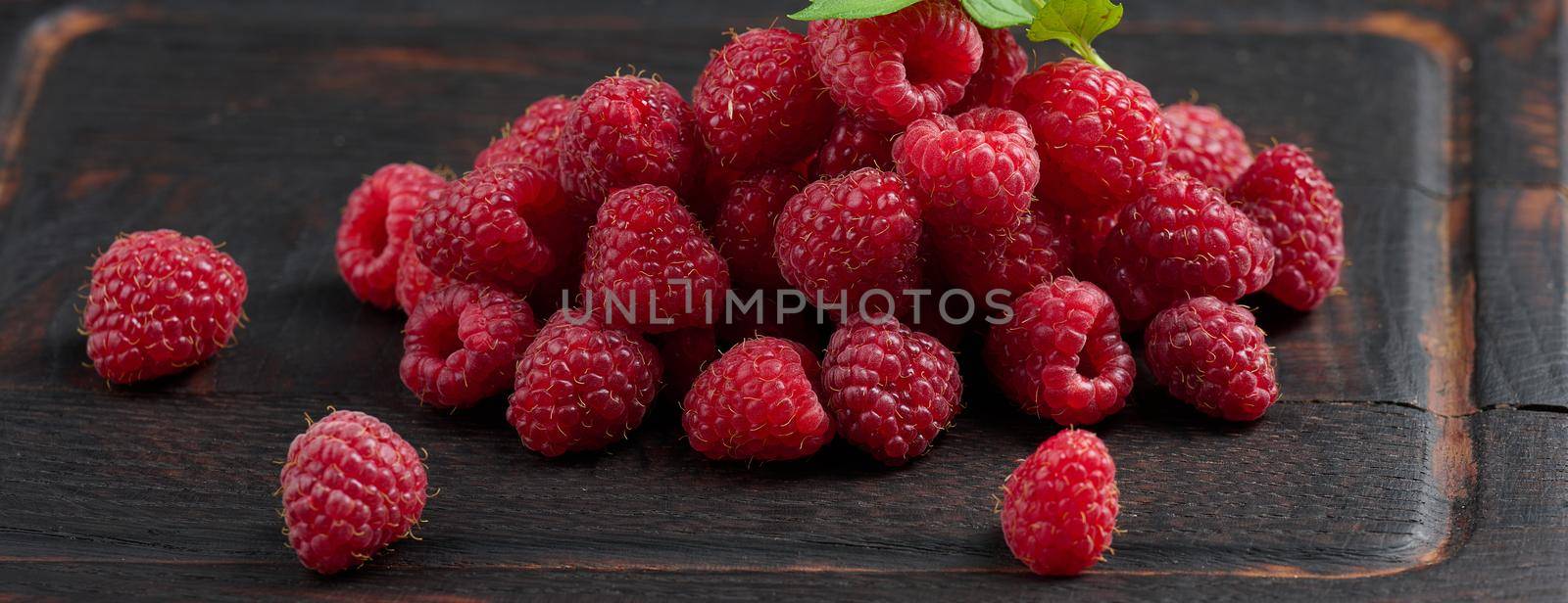 Ripe red raspberries on a brown wooden board