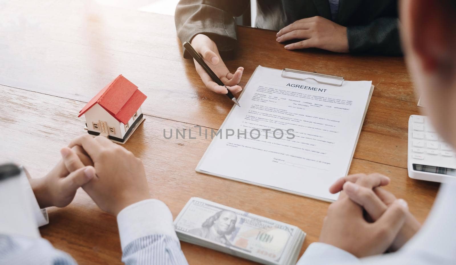 The real estate agent draws up a house contract after the client has paid the house deposit. discussion, negotiation, close the deal by wichayada