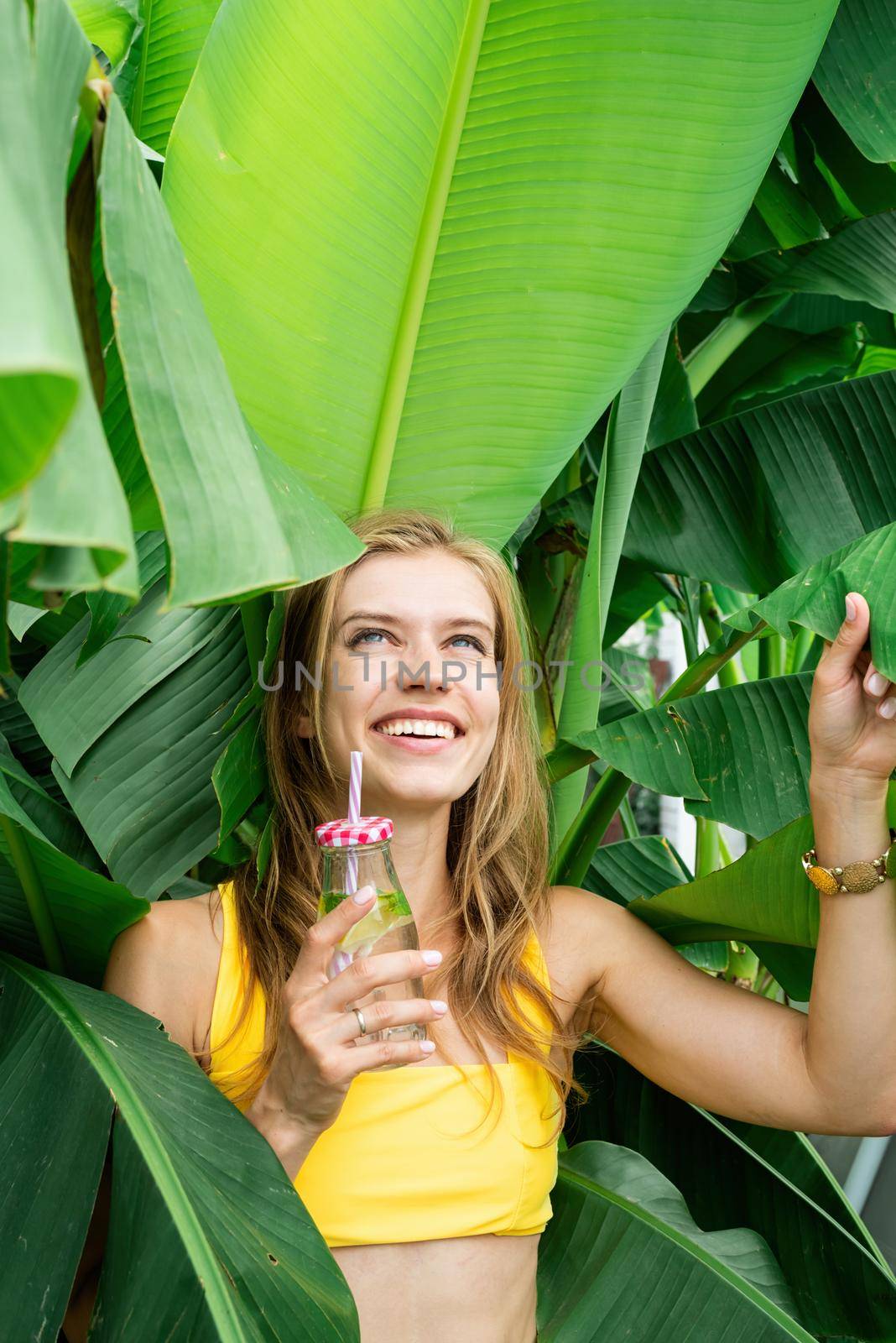 Summer vacation. Beautiful woman in yellow swimsuit with long hair and palm leaves. Beautiful caucasian girl in stylish swimwear in tropical nature