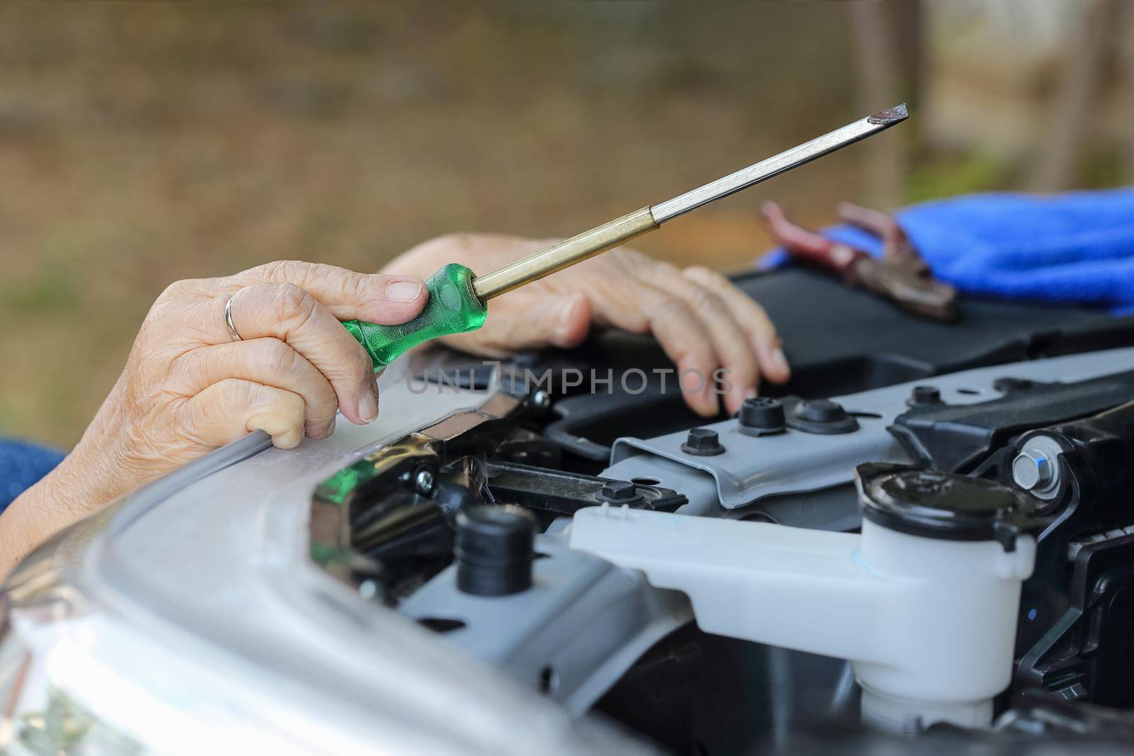 Elderly woman repairing her car