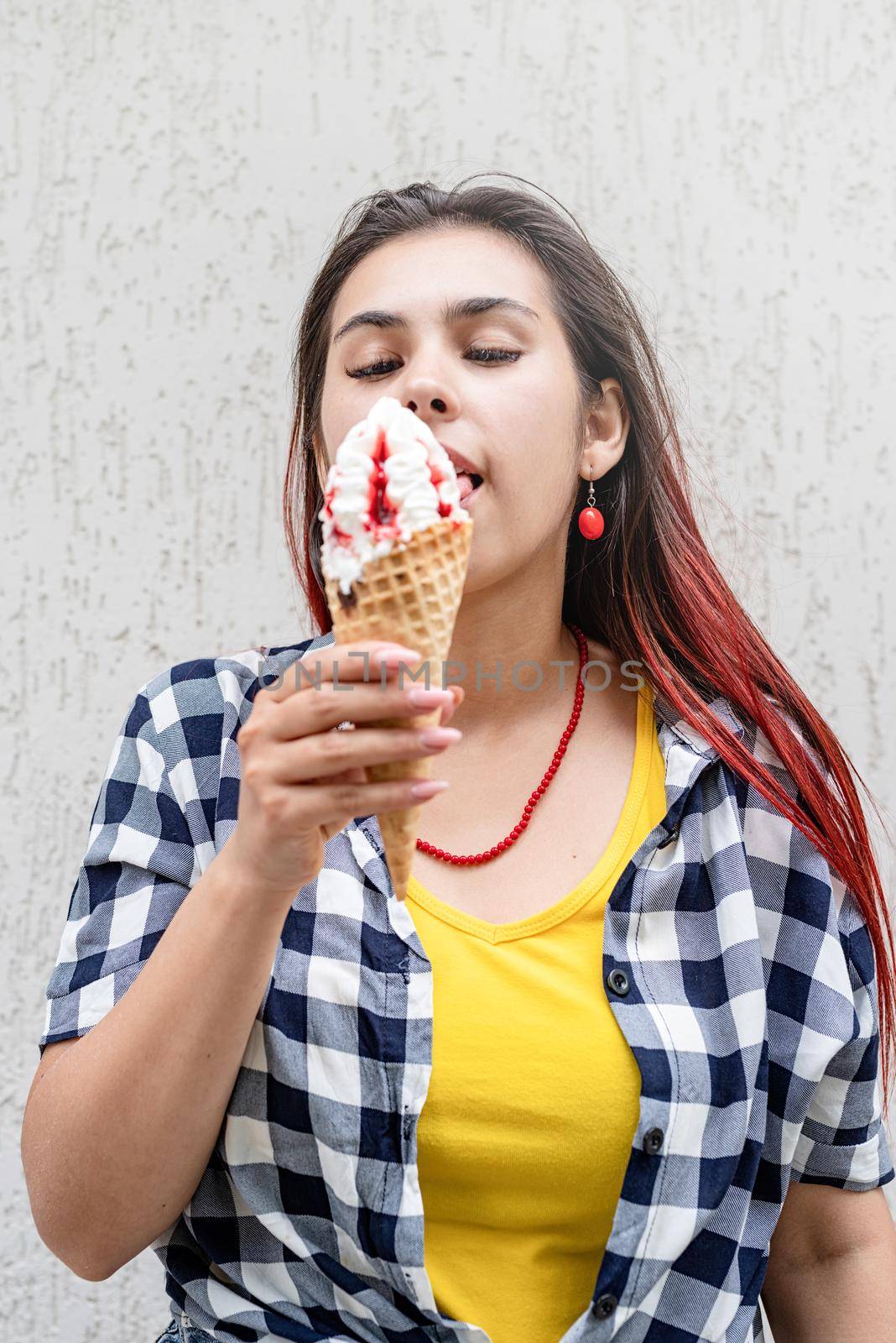 cheerful trendy woman with red hair eating ice cream at street by Desperada