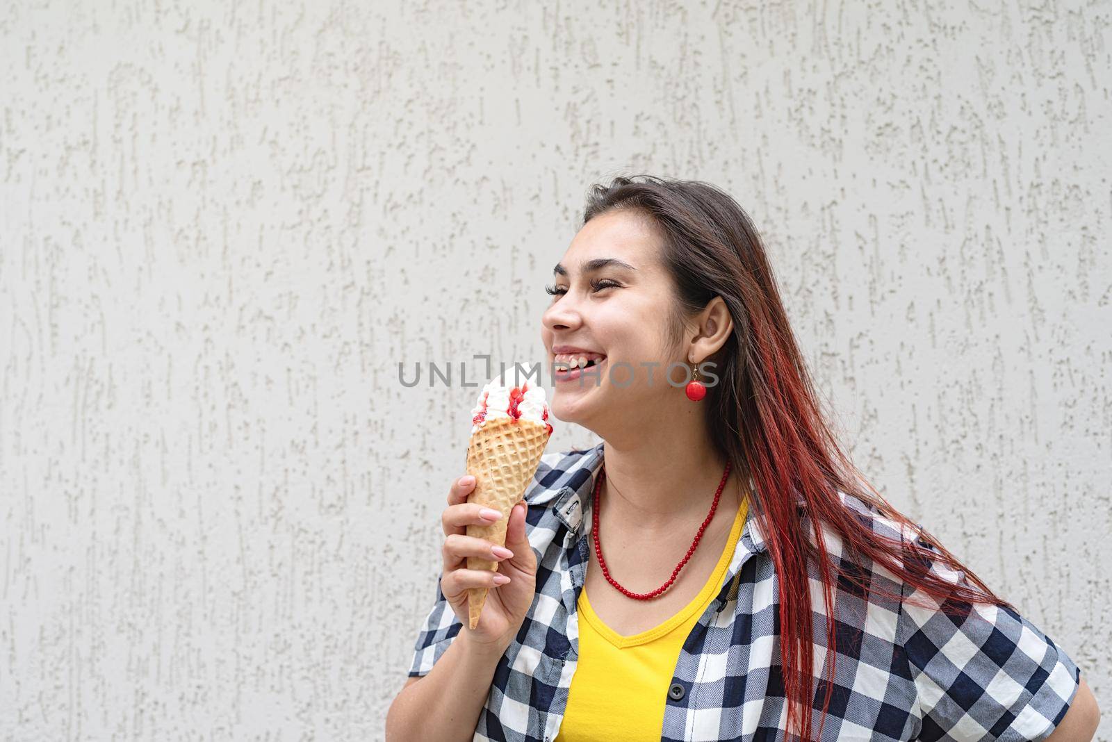 Attractive young woman in summer clothes and sunglasseseating ice cream at street