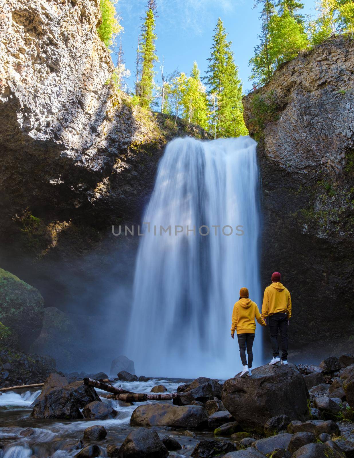 Beautiful waterfall in Canada, couple visit Helmcken Falls, the most famous waterfall in Wells Gray Provincial Park in British Columbia, Canada. couple of men and women standing by a waterfall