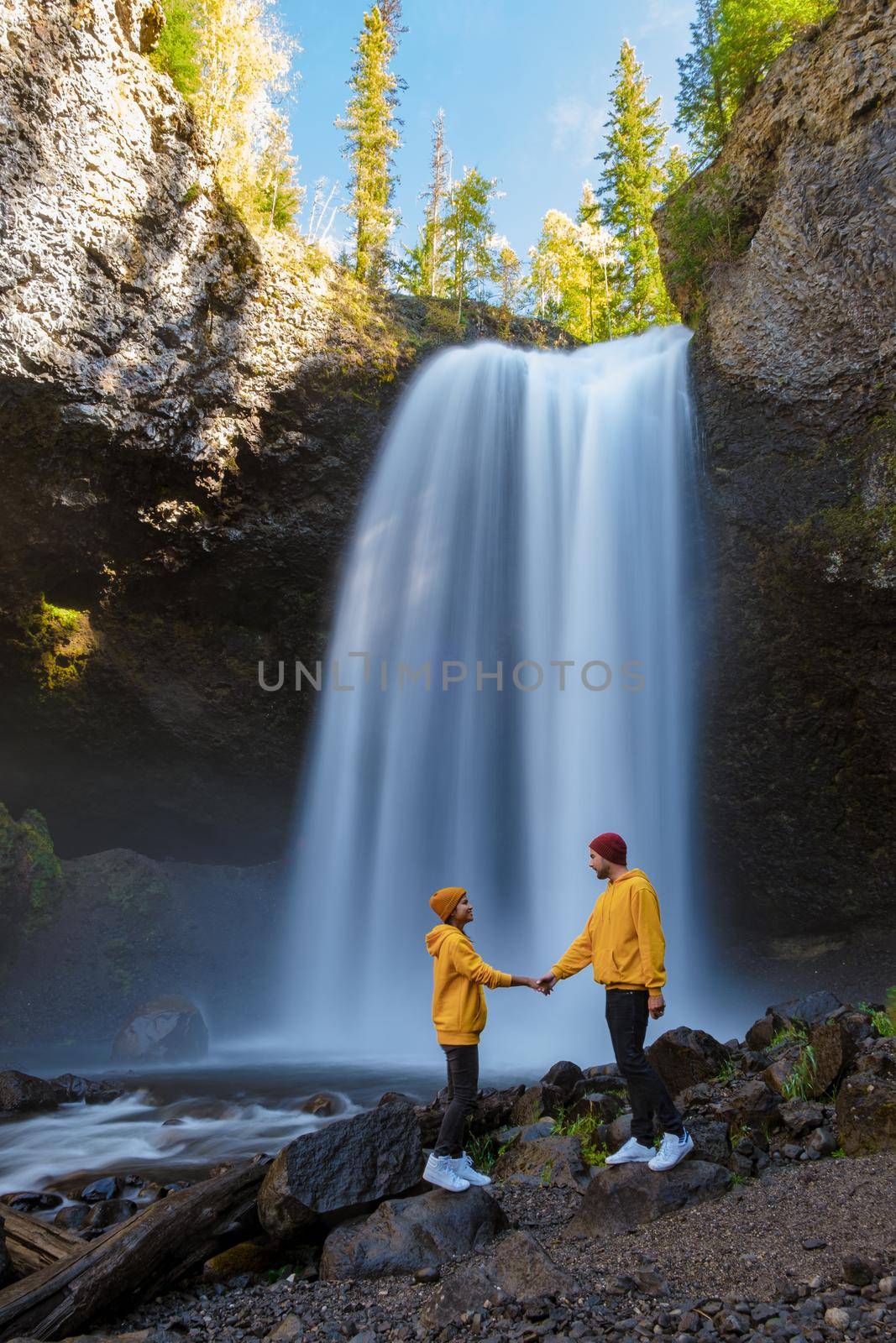 Beautiful waterfall in Canada, couple visit Helmcken Falls, the most famous waterfall in Wells Gray Provincial Park in British Columbia, Canada. couple of men and women standing by a waterfall