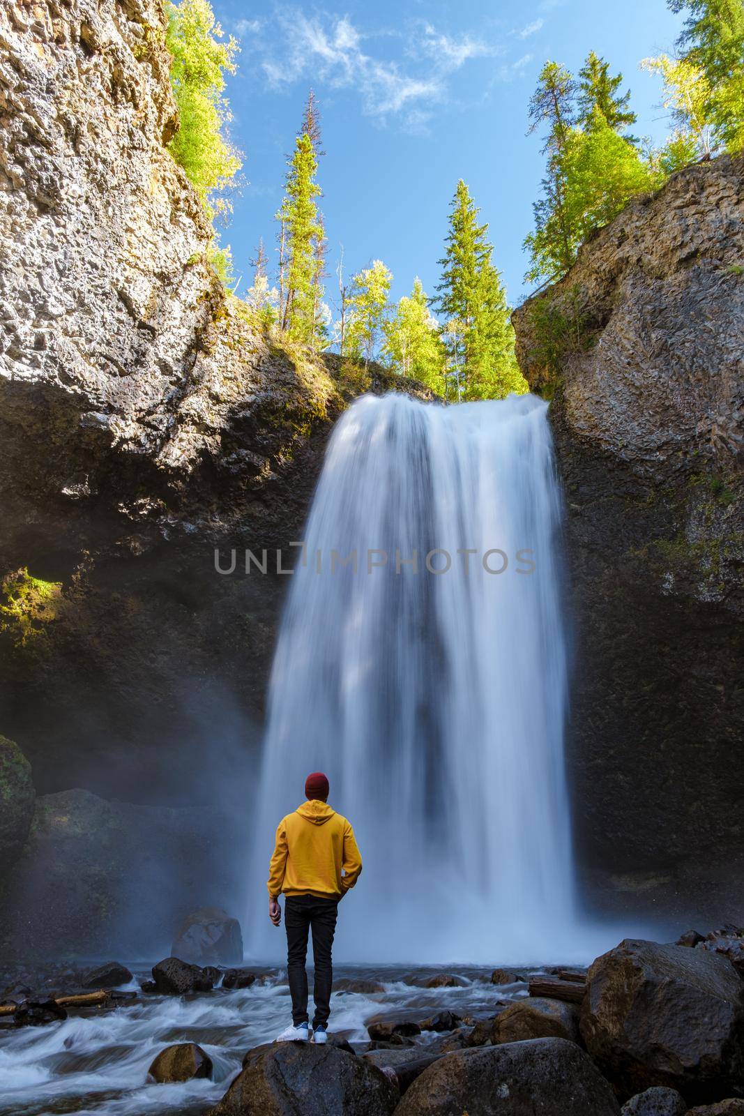 Beautiful waterfall in Canada, couple visit Helmcken Falls, the most famous waterfall in Wells Gray Provincial Park in British Columbia, Canada. young men standing looking at a waterfall