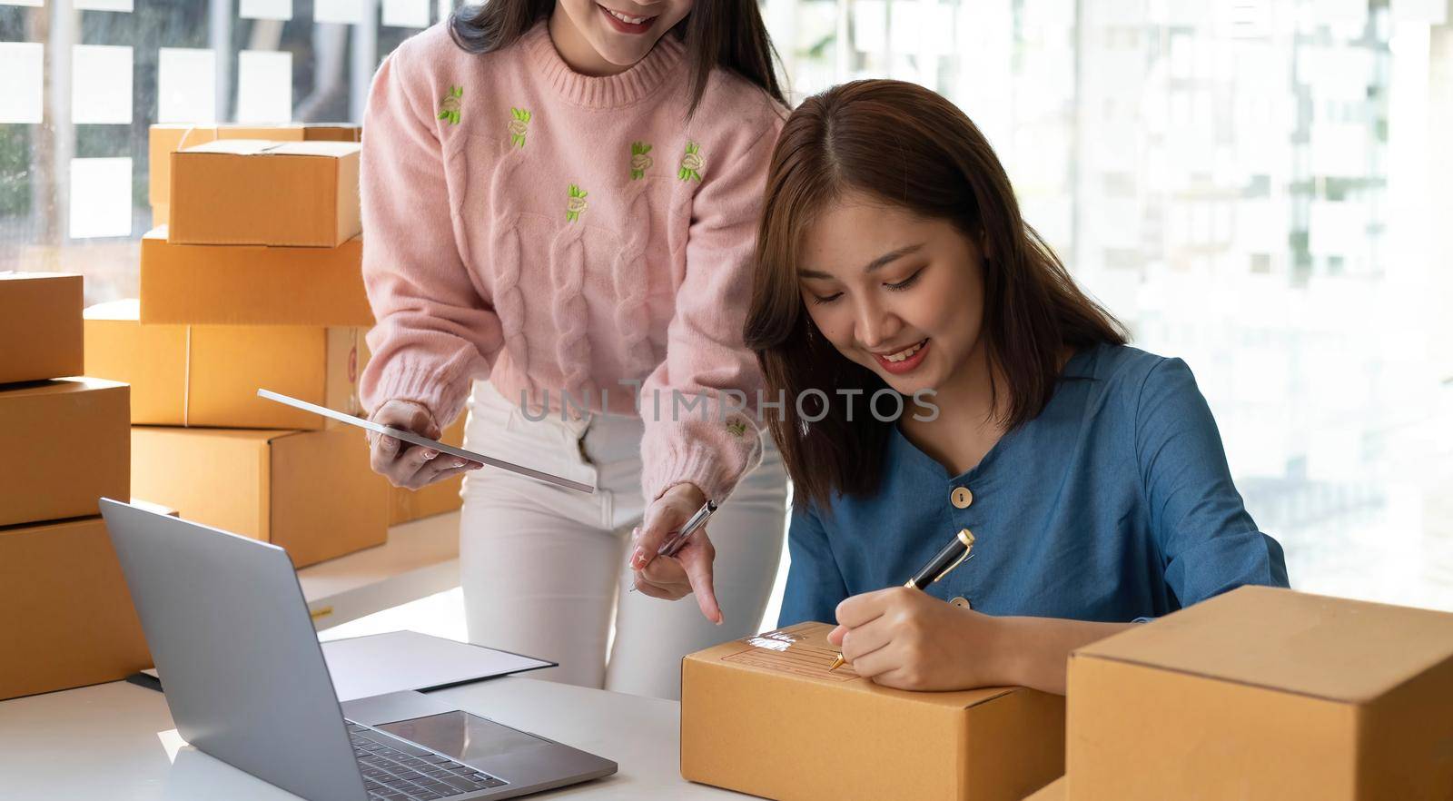 Portrait of Starting small businesses SME owners, two Asian woman check online orders Selling products working with boxs freelance work at home office, sme business online small medium enterprise.