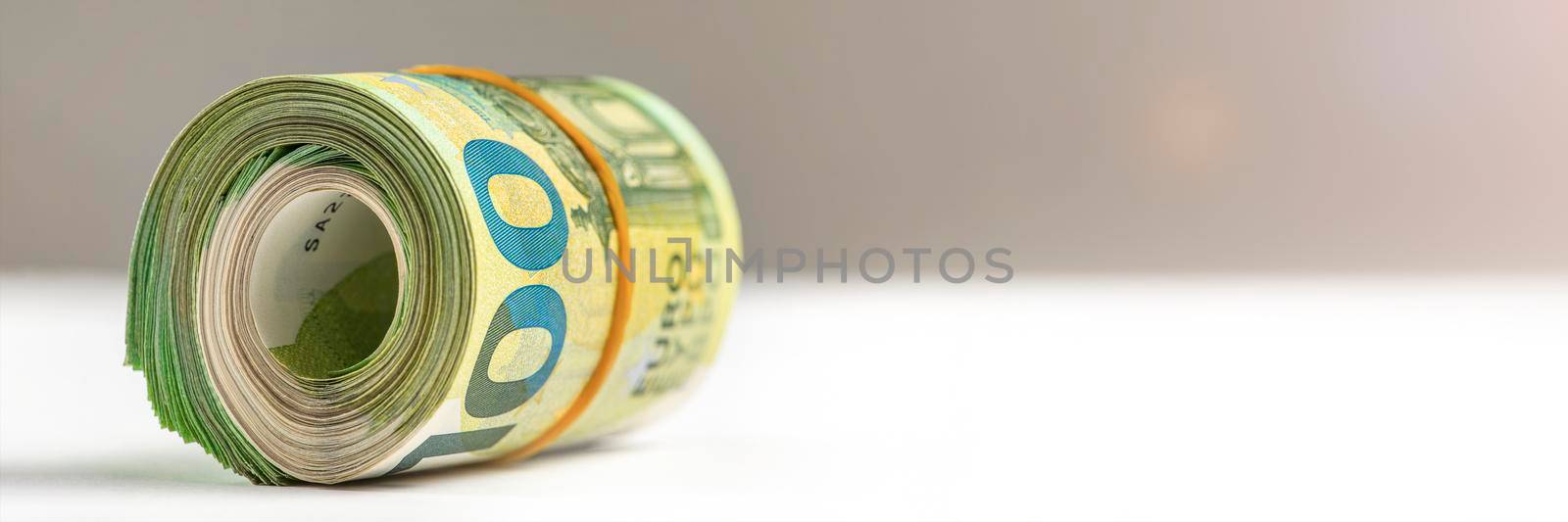 Roll of money. Roll of 100 euro banknotes. Euro banknotes rolled up on a gray background. The concept of financial assistance, real estate purchase, loan or insurance payment. by SERSOL