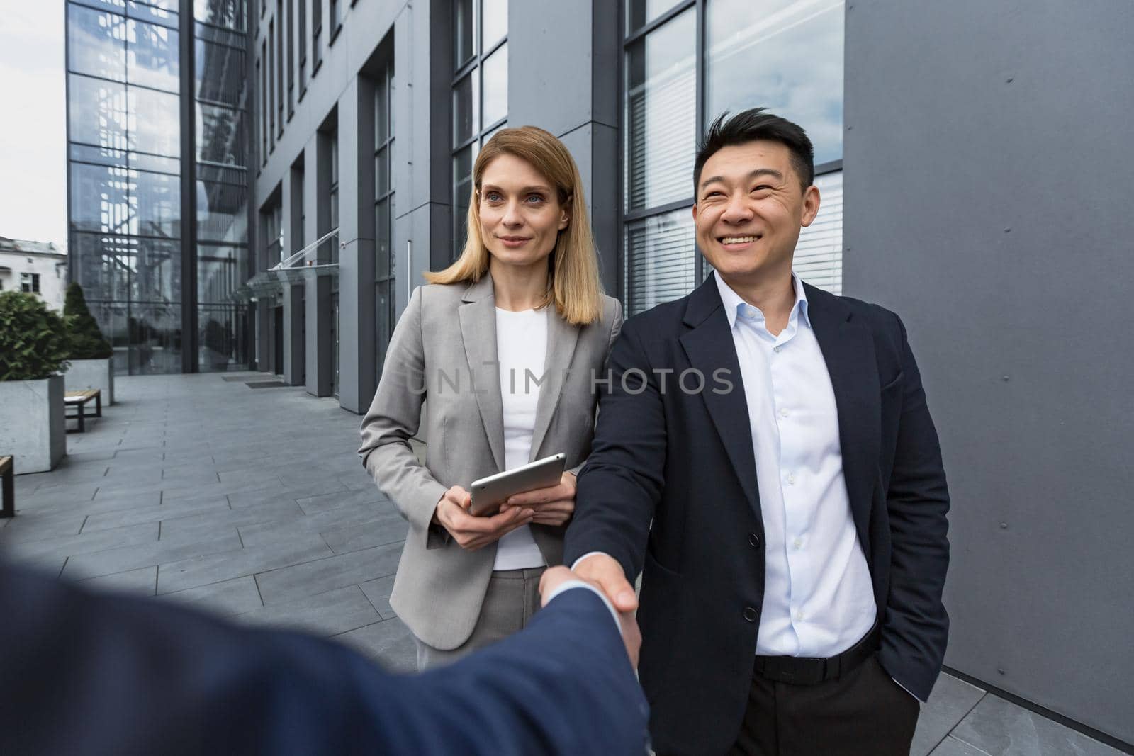 Business meet, three business colleagues greet each other, men shake hand by voronaman