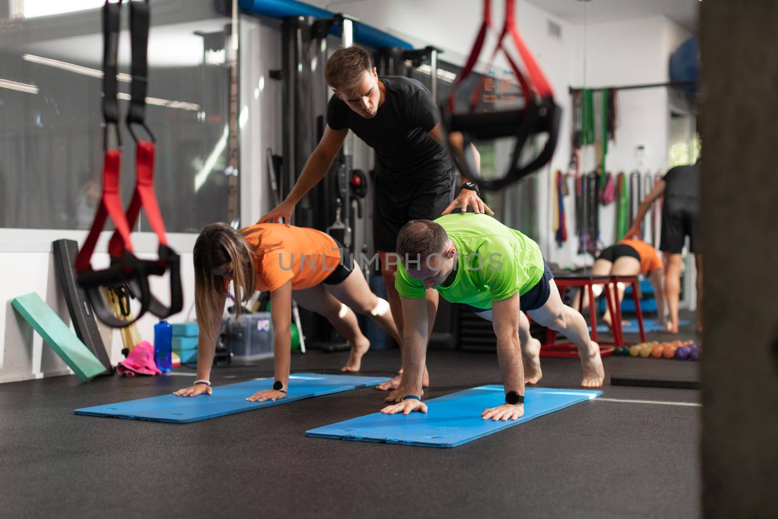 Two trainees, man and woman exercising at the gym by stockrojoverdeyazul