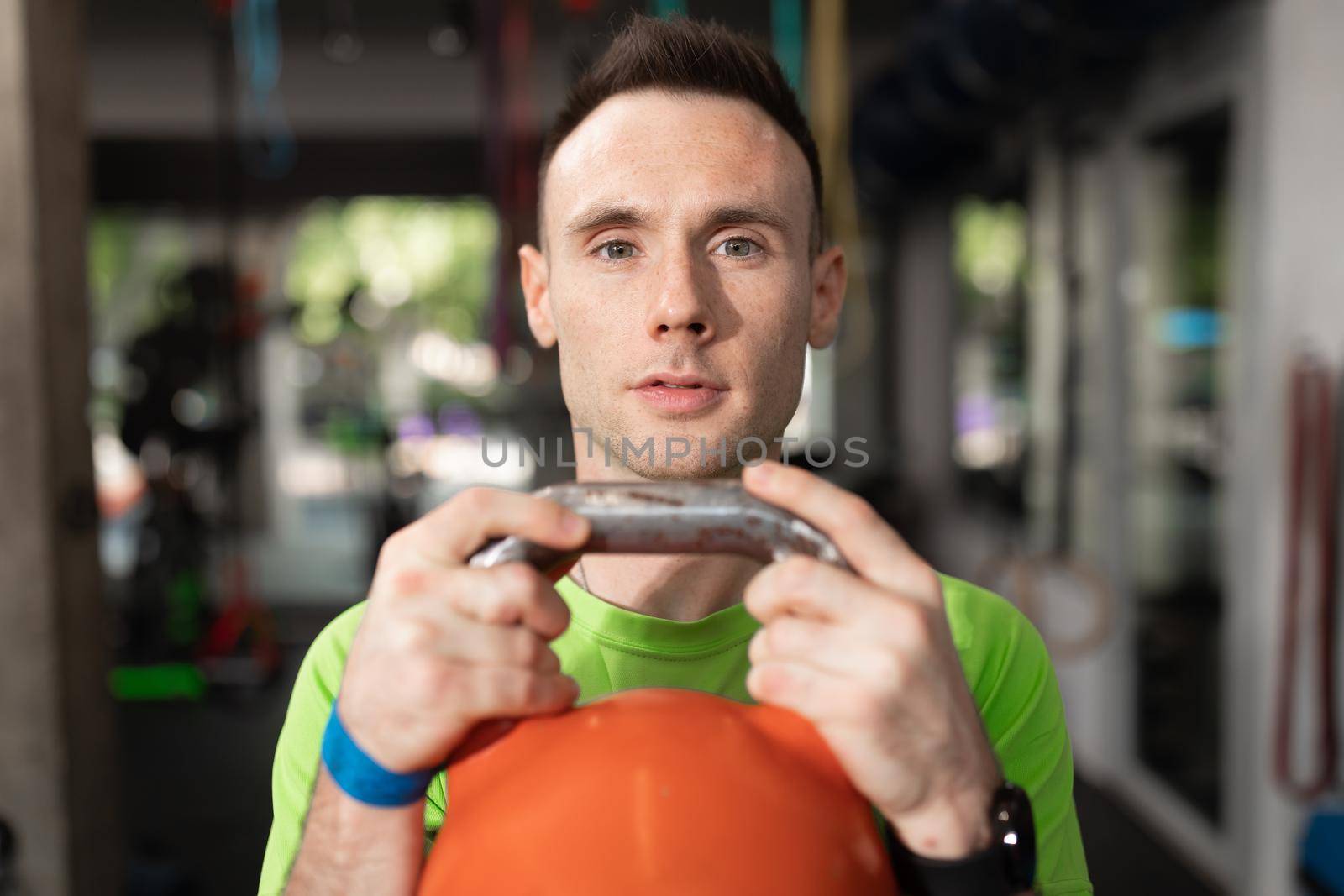 Portrait of a male trainee lifting a kettlebell during a work out session at the local sport and fitness center