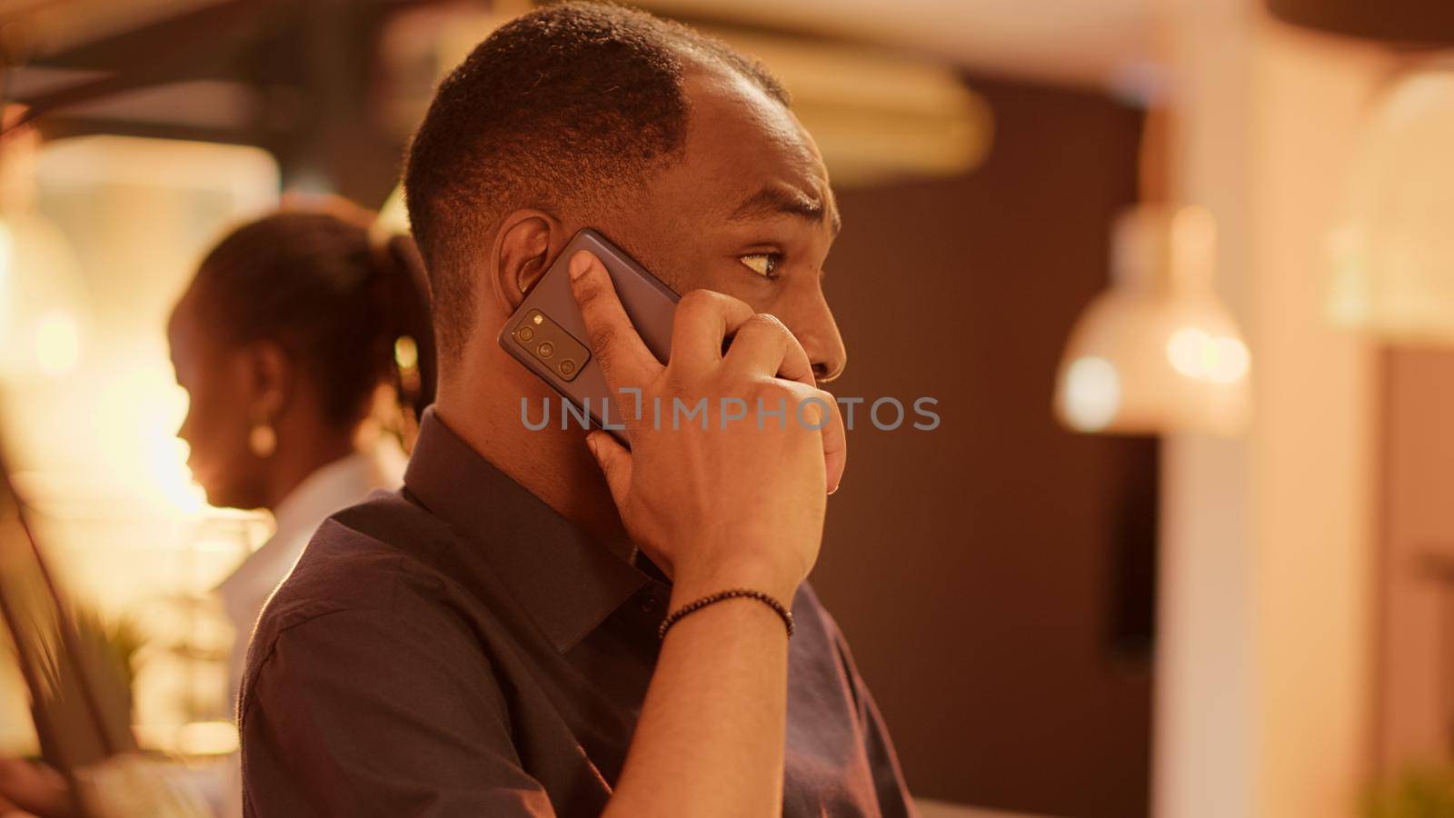 African american man talking on mobile phone call at office desk by DCStudio