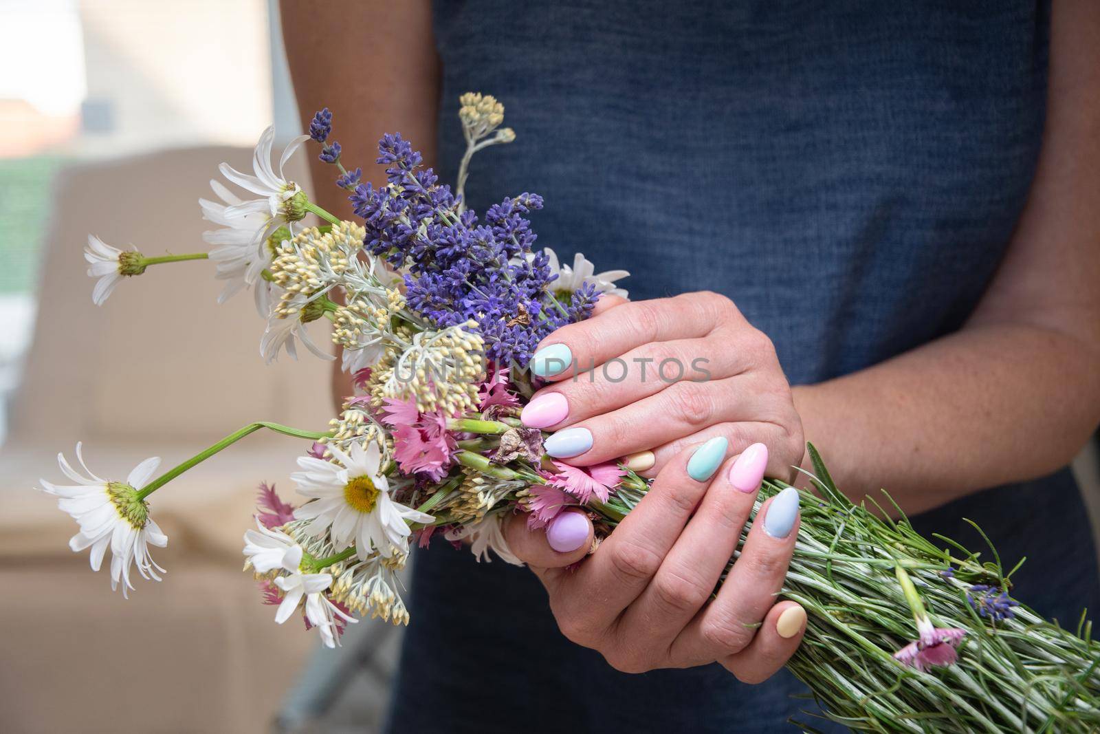 a young woman with a beautiful summer manicure holds a bouquet of wild flowers in pastel shades. High quality photo