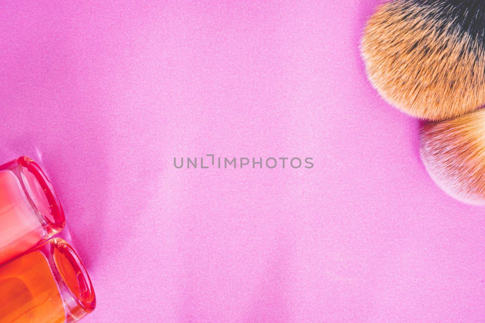 Flatlay of make up and beauty products on a pink background.