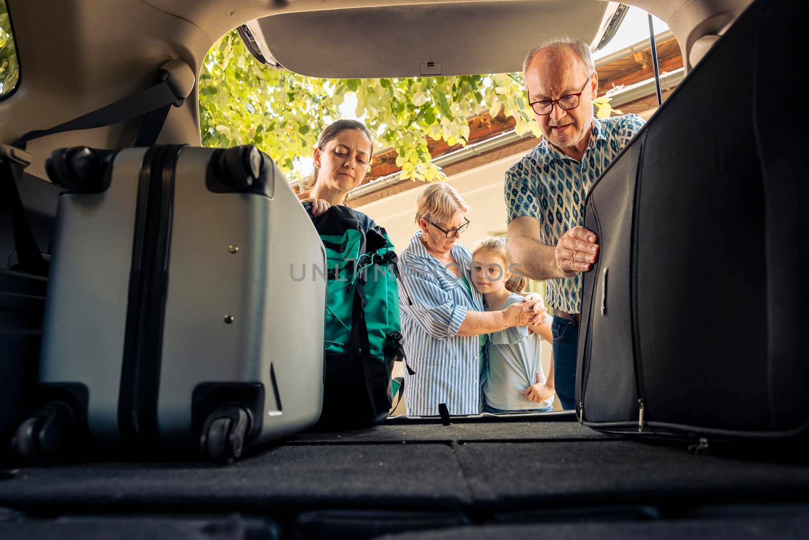 People loading suitcase and luggage in trunk by DCStudio