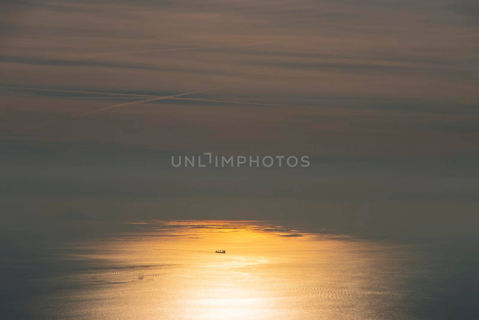 A ship in the middle of the ocean lit up by orange sunlight on water by StefanMal