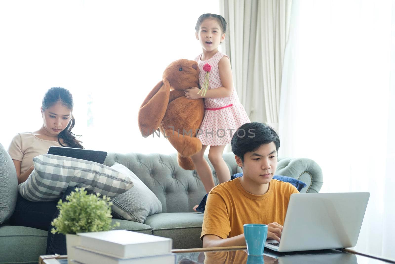 Concept of work from home and home family education. father mother and son are sitting at the desk. Business woman works on the Internet in a laptop.