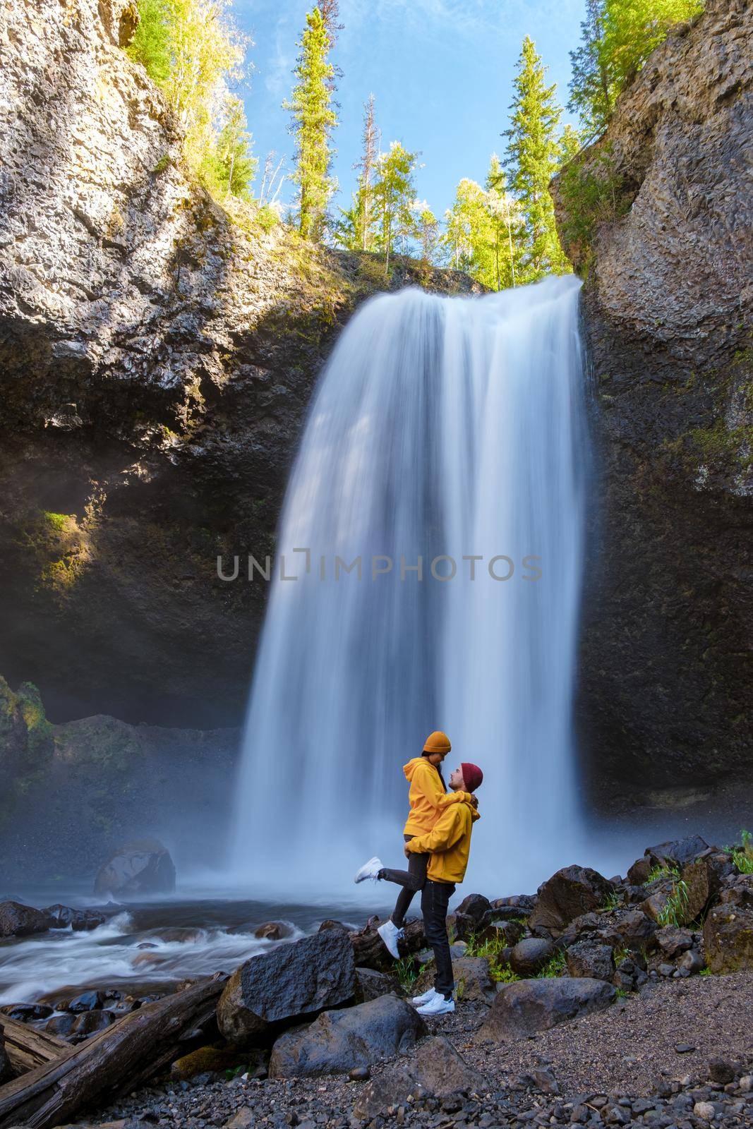 Moul Falls Canada is a Beautiful waterfall in Canada, couple of visits to Moul Falls, the most famous waterfall in Wells Gray Provincial Park. a couple of men and women standing by a waterfall