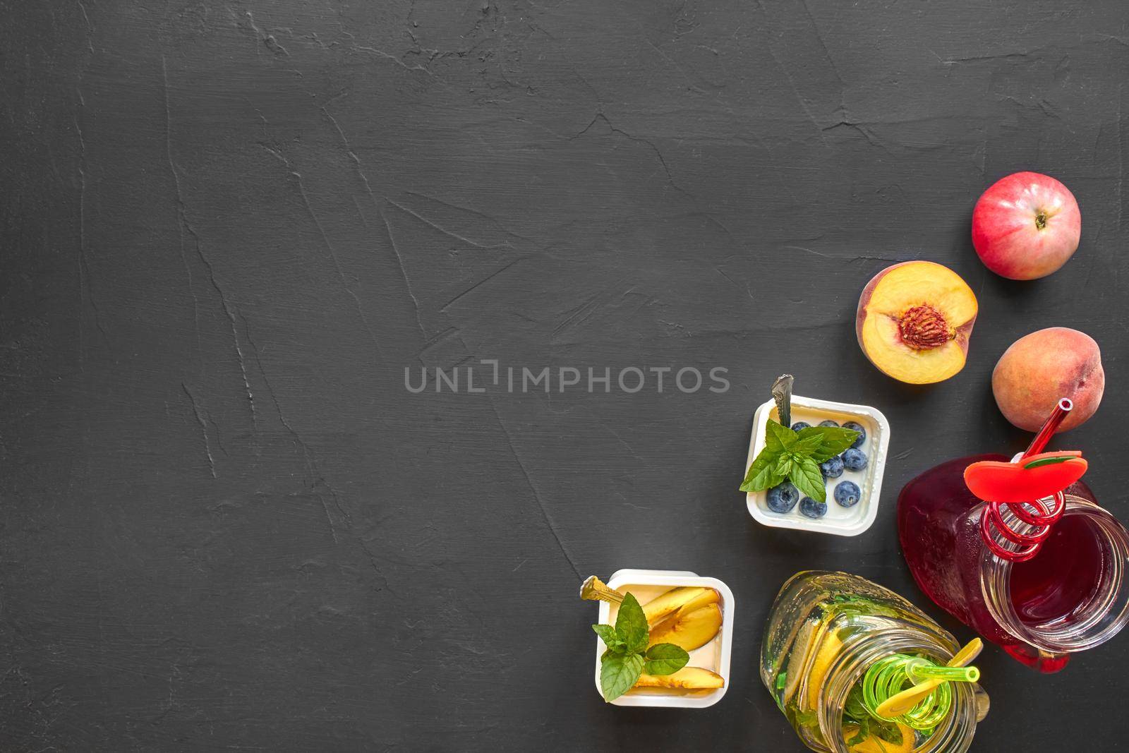Top view of healthy and gourmet snack on a black background with copy space. Fresh fruits, natural yoghurt and a beverages with funny tubules for tasty and nutritious meal.