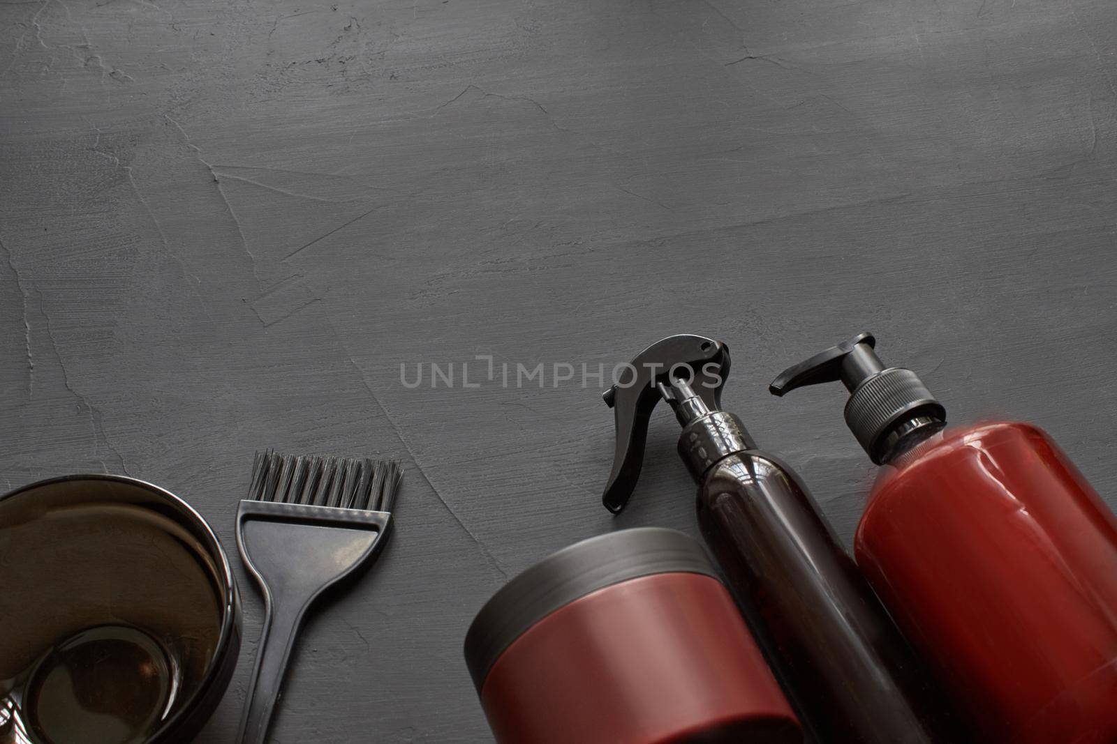 Top view of a professional hairdresser kit with copy space on a black background. Coloring brush, plastic bowl and barbers hair care products. Branding mockup.